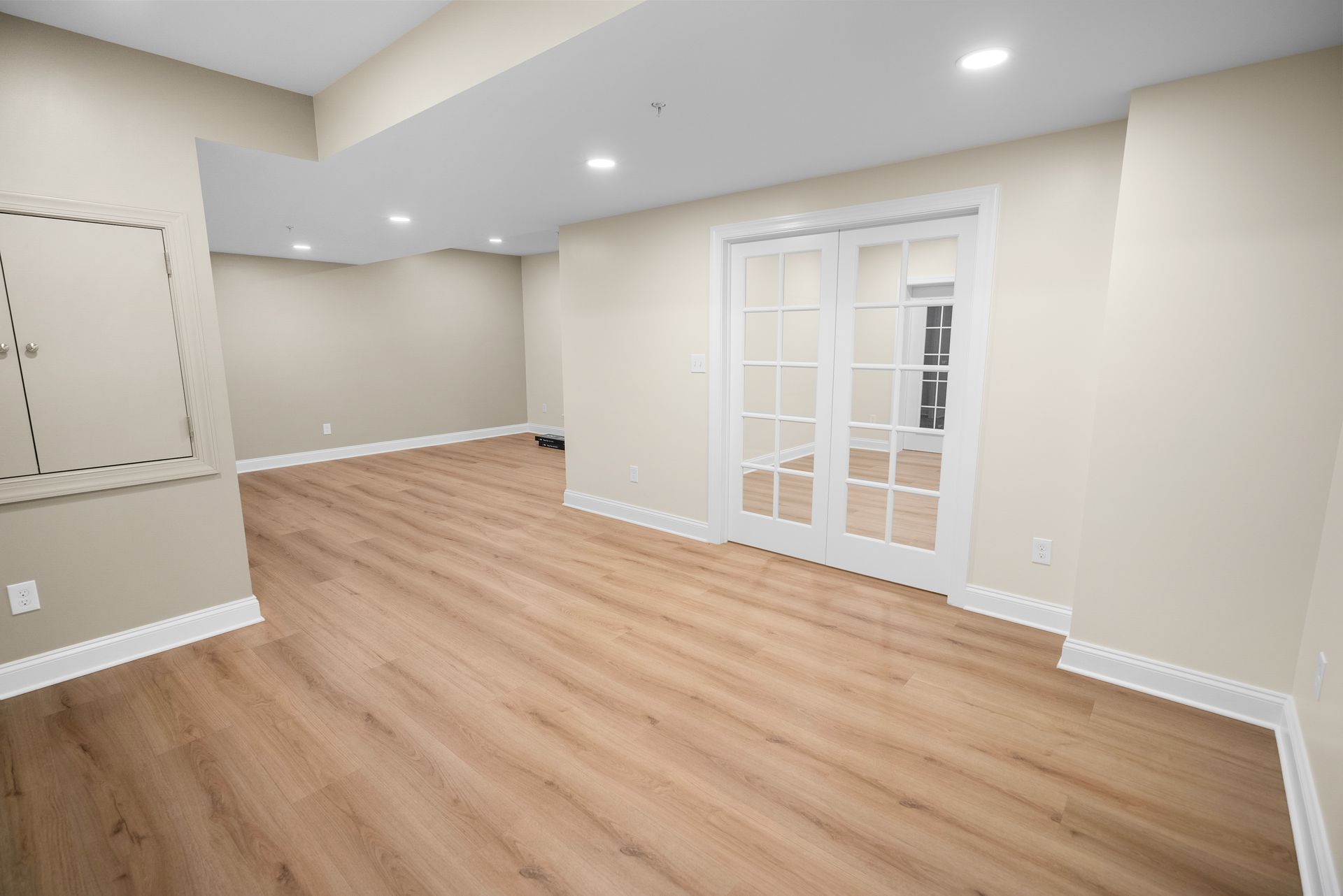 Interior hallway in a finished basement leading to private flex rooms and utility storage.