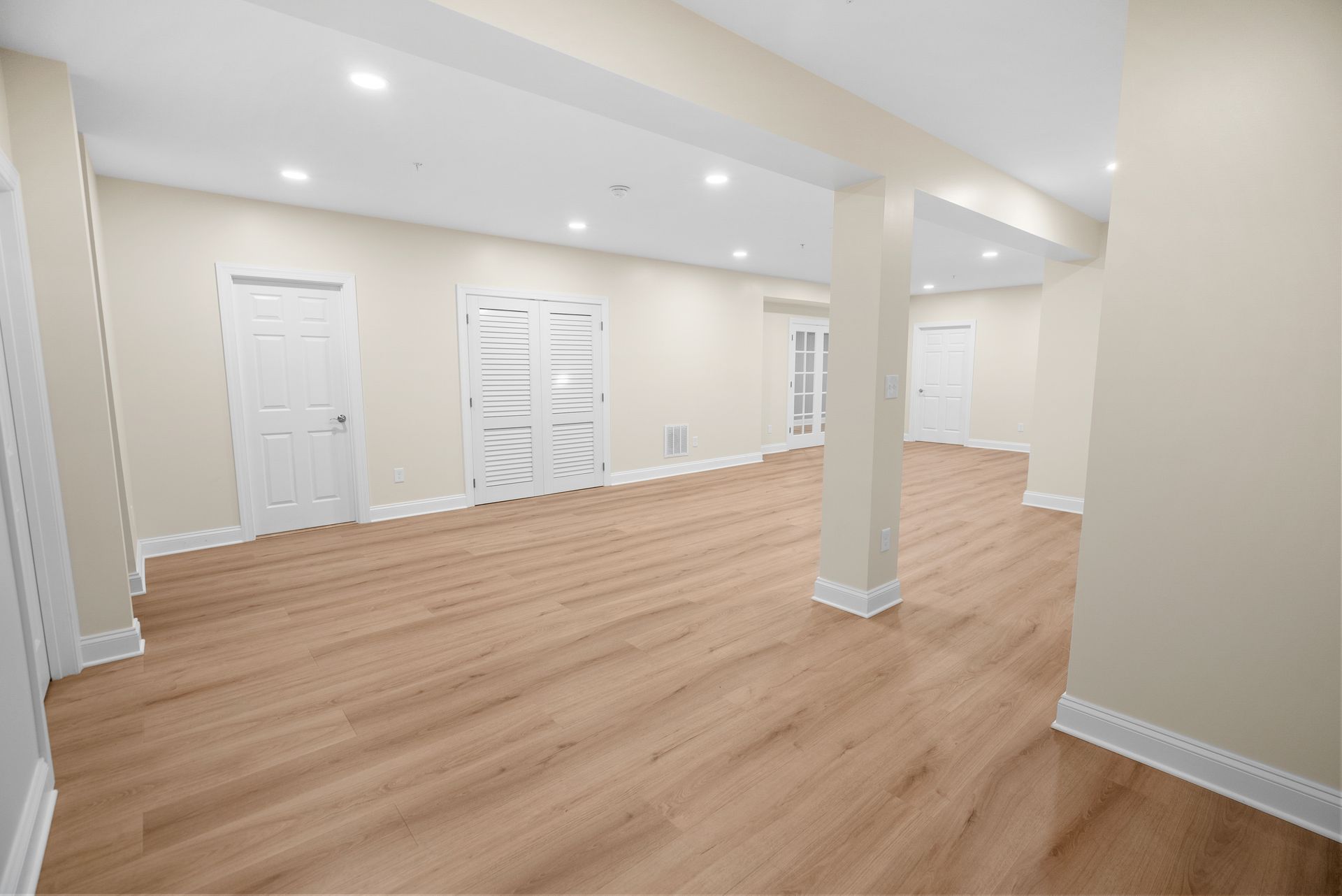 Modern finished basement room with sleek white sliding barn door and crisp baseboard trim.