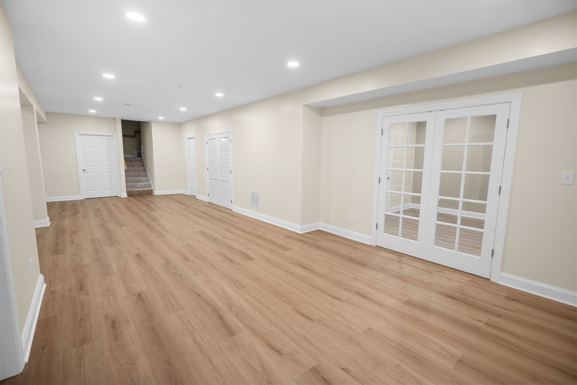 Custom white double French glass doors installed in a bright finished basement suite.