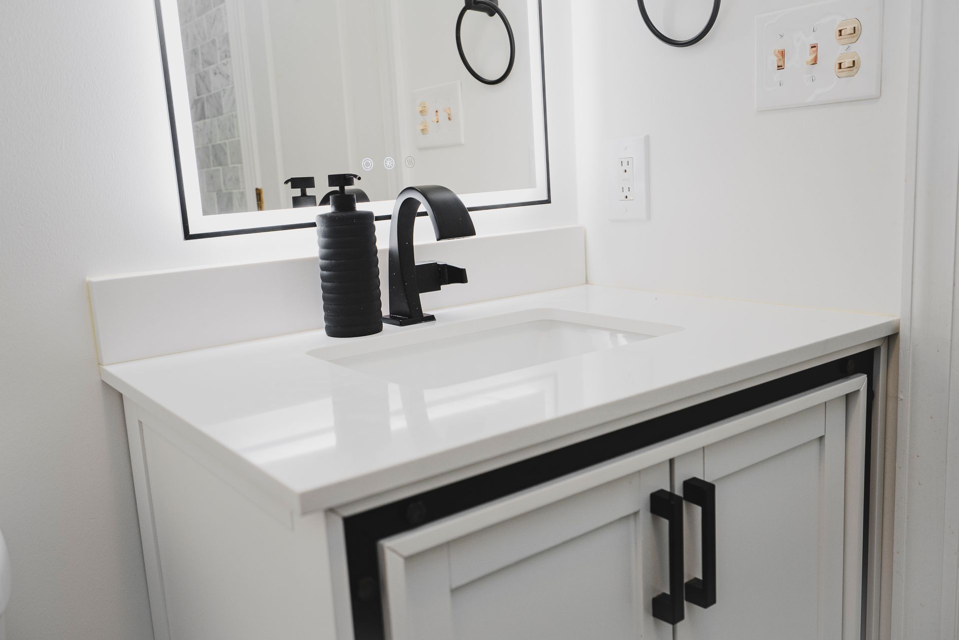 Minimalist black bathroom faucet on a white vanity top.
