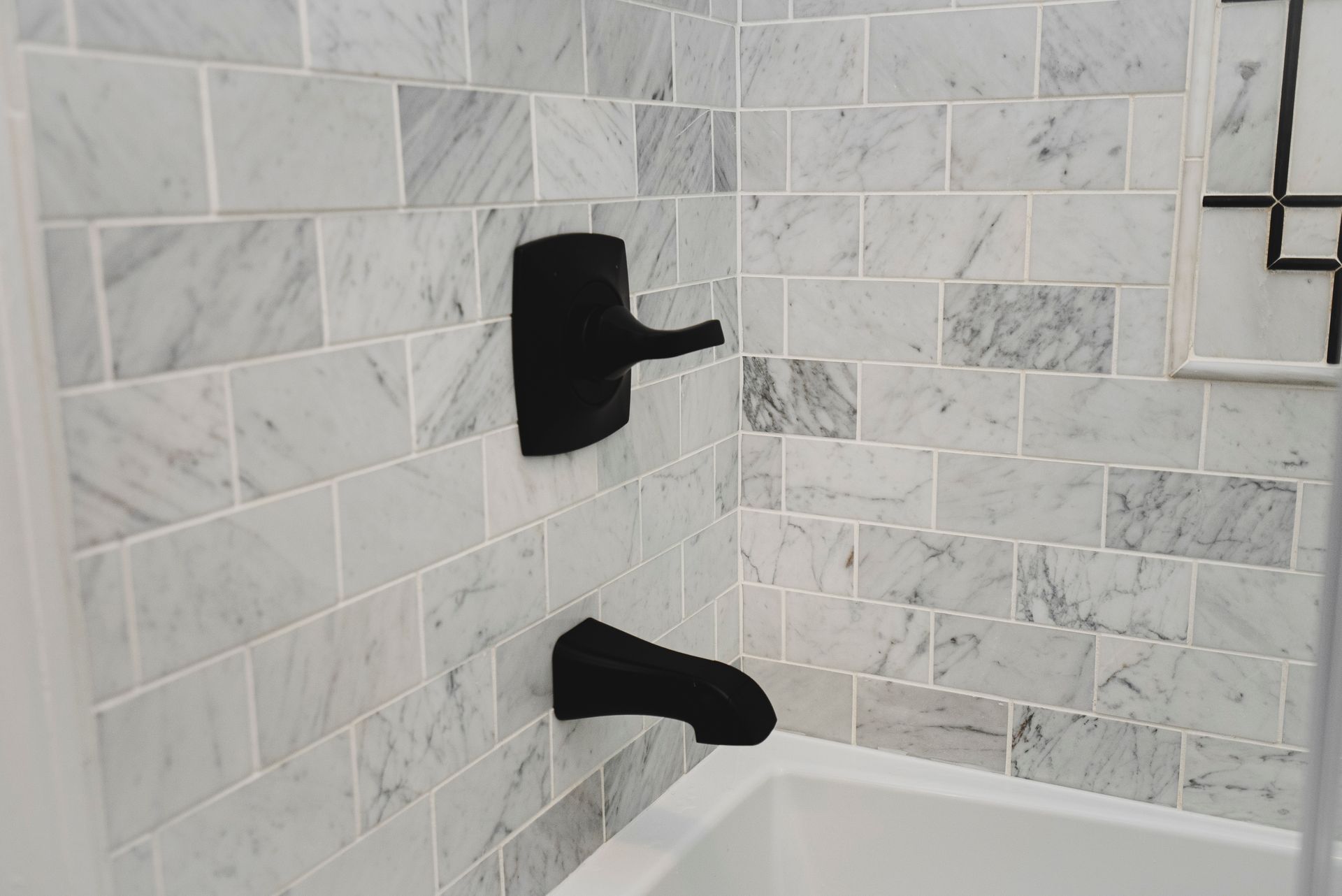 Close-up of contemporary matte black shower fixtures against light tile.