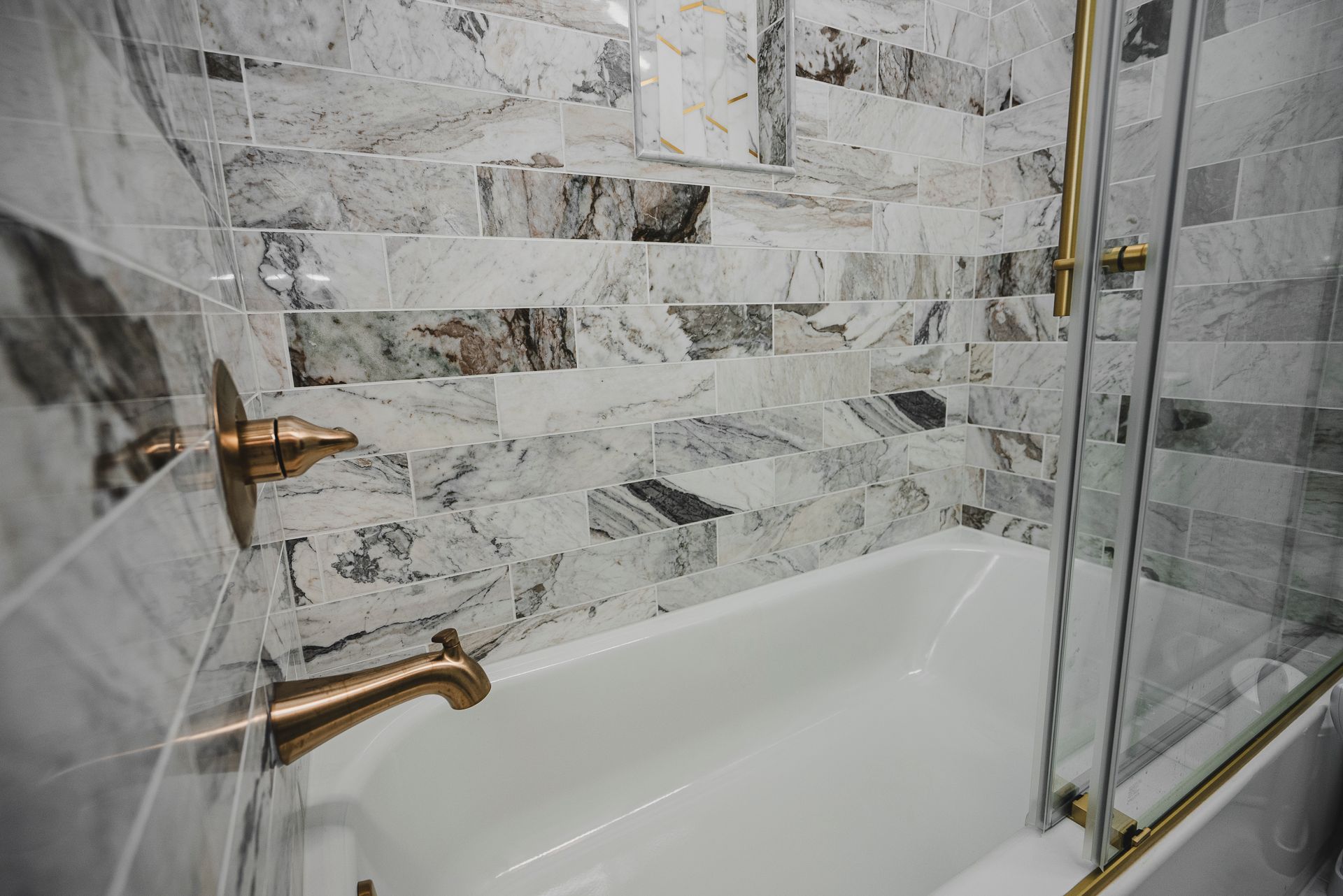 Elegant white bathroom remodel with brushed gold Delta shower fixtures and marble subway tile.