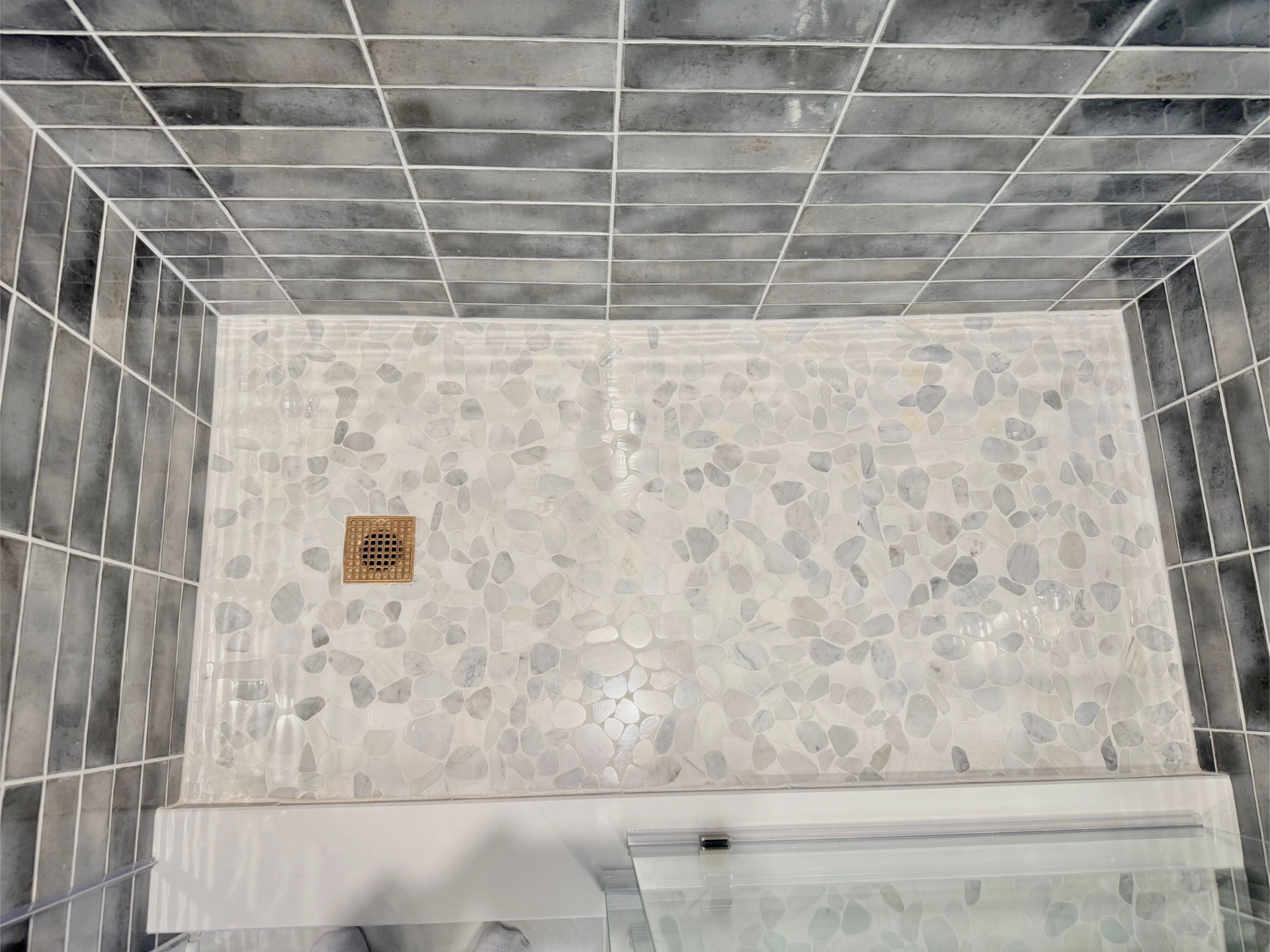 Modern hall bathroom remodel with a custom walk-in shower, patterned tile, and a gold-framed round mirror.