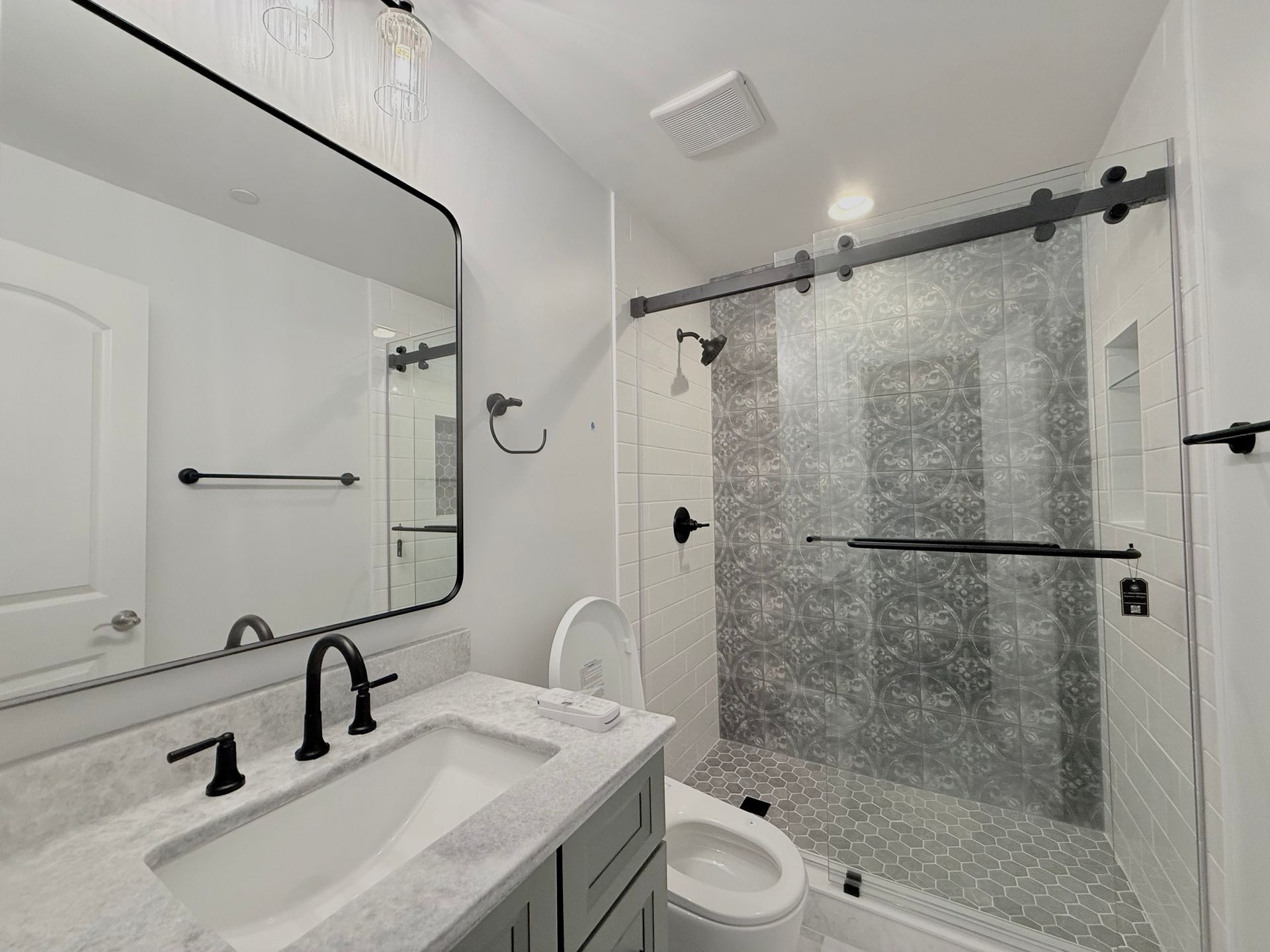 A full view of a modern basement bathroom remodel in Hampstead, MD, with a new shower and a vanity with a large mirror.