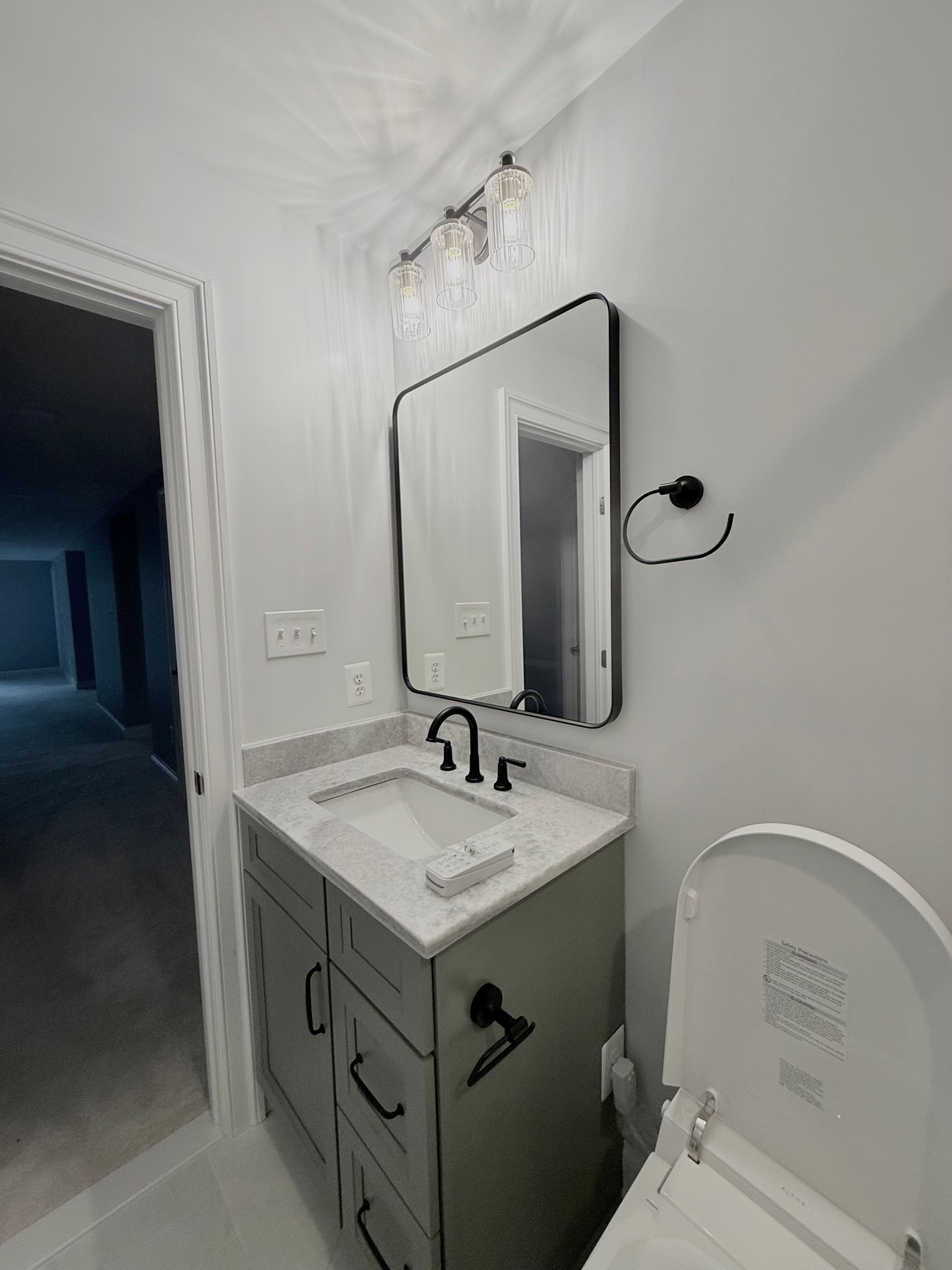 A new bathroom vanity with a white countertop and a matte black faucet in a Hampstead bathroom renovation.