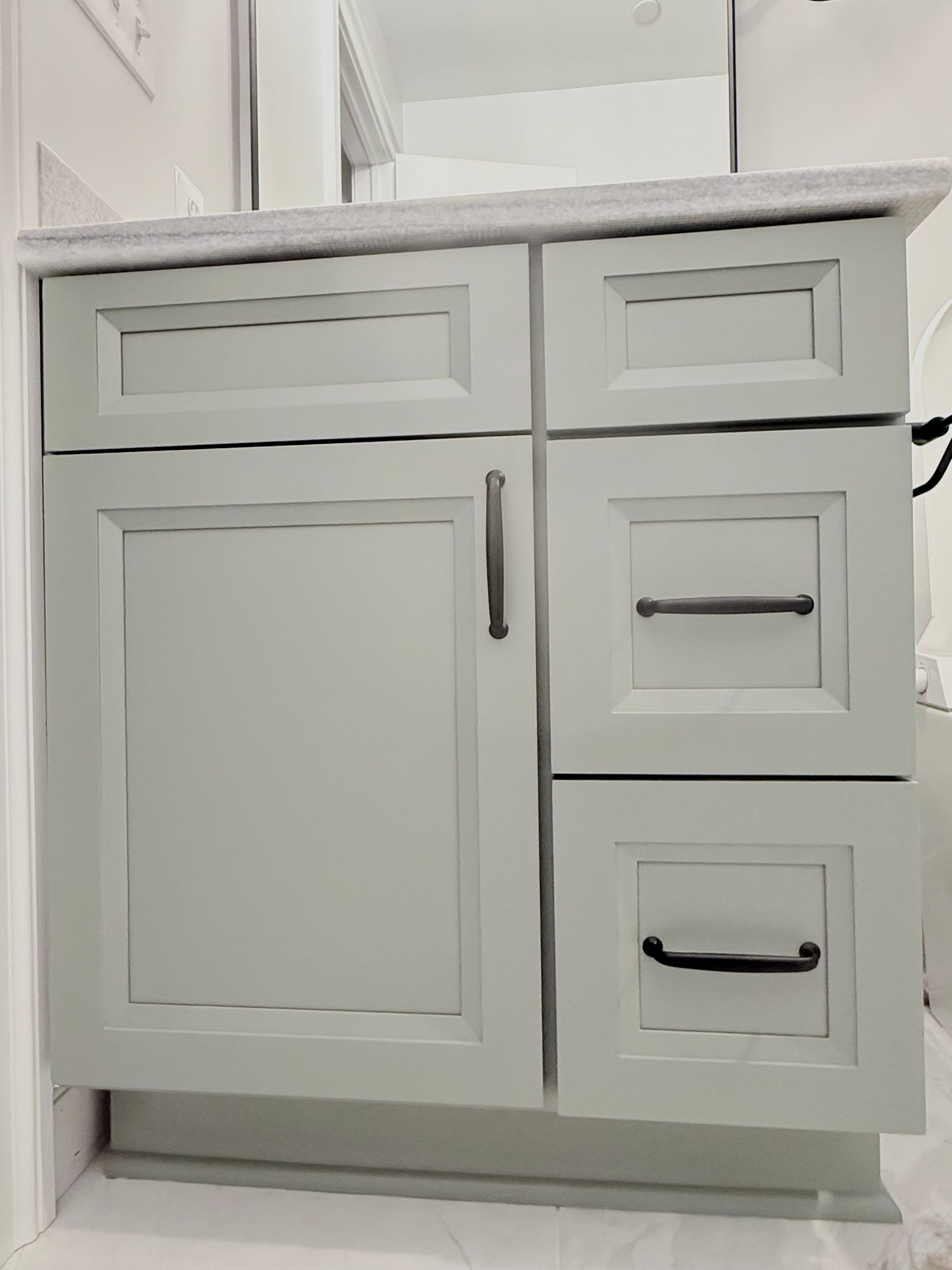 A new vanity with a modern mirror and matte black towel ring in a renovated bathroom.