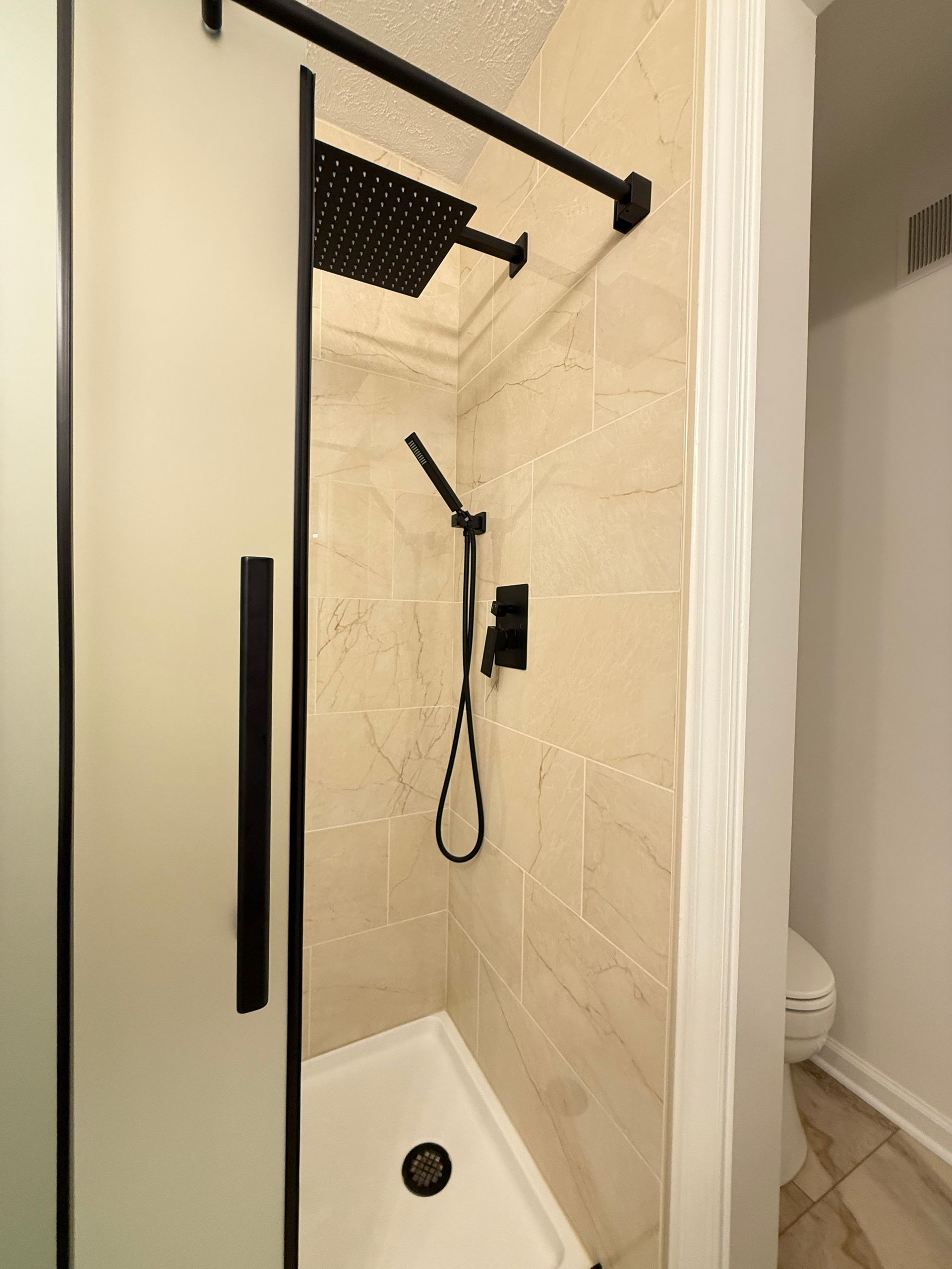 Sleek frosted glass sliding shower door installation with matte black hardware for modern bathroom.