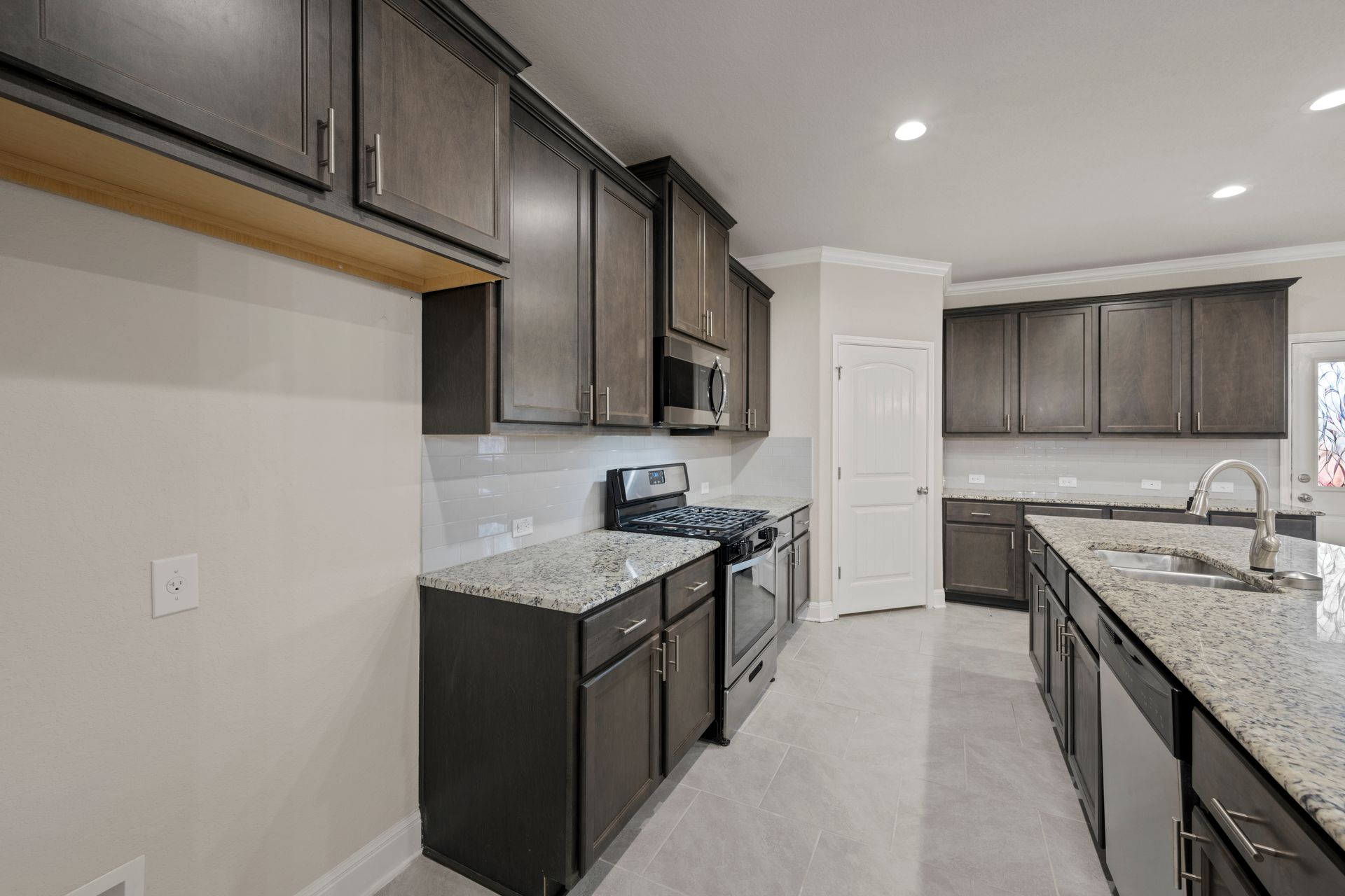 Large granite island in a dark cabinet kitchen remodel in Columbia, Maryland, featuring shaker cabinets and stainless steel appliances.