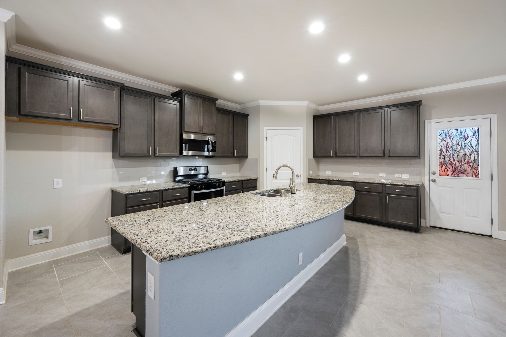 Large granite island in a dark cabinet kitchen remodel in Columbia, Maryland, featuring shaker cabinets and stainless steel appliances.
