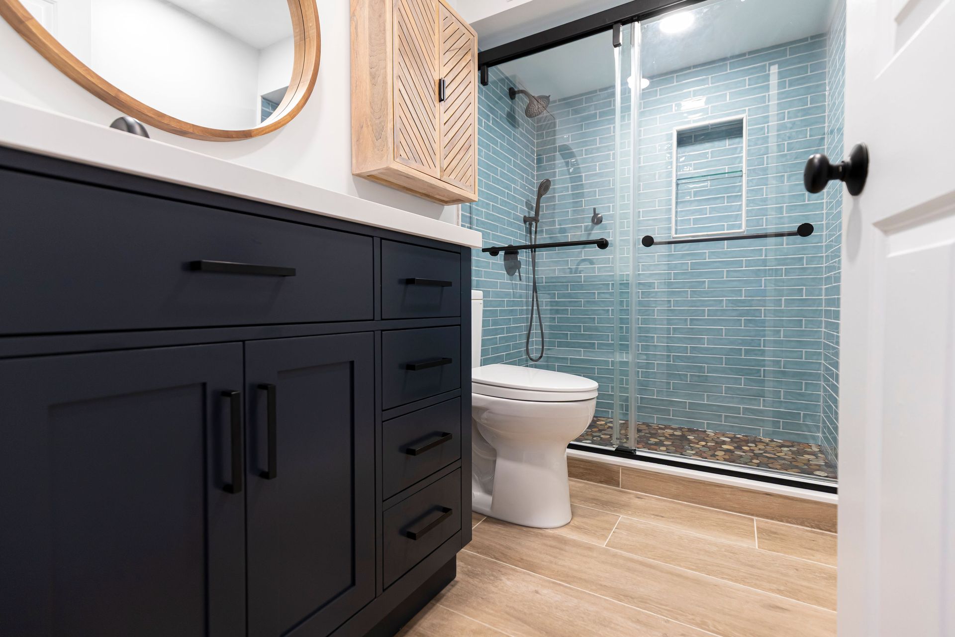 Full view of a black vanity installation and custom walk-in shower with blue tile in an Ellicott City bathroom remodel.