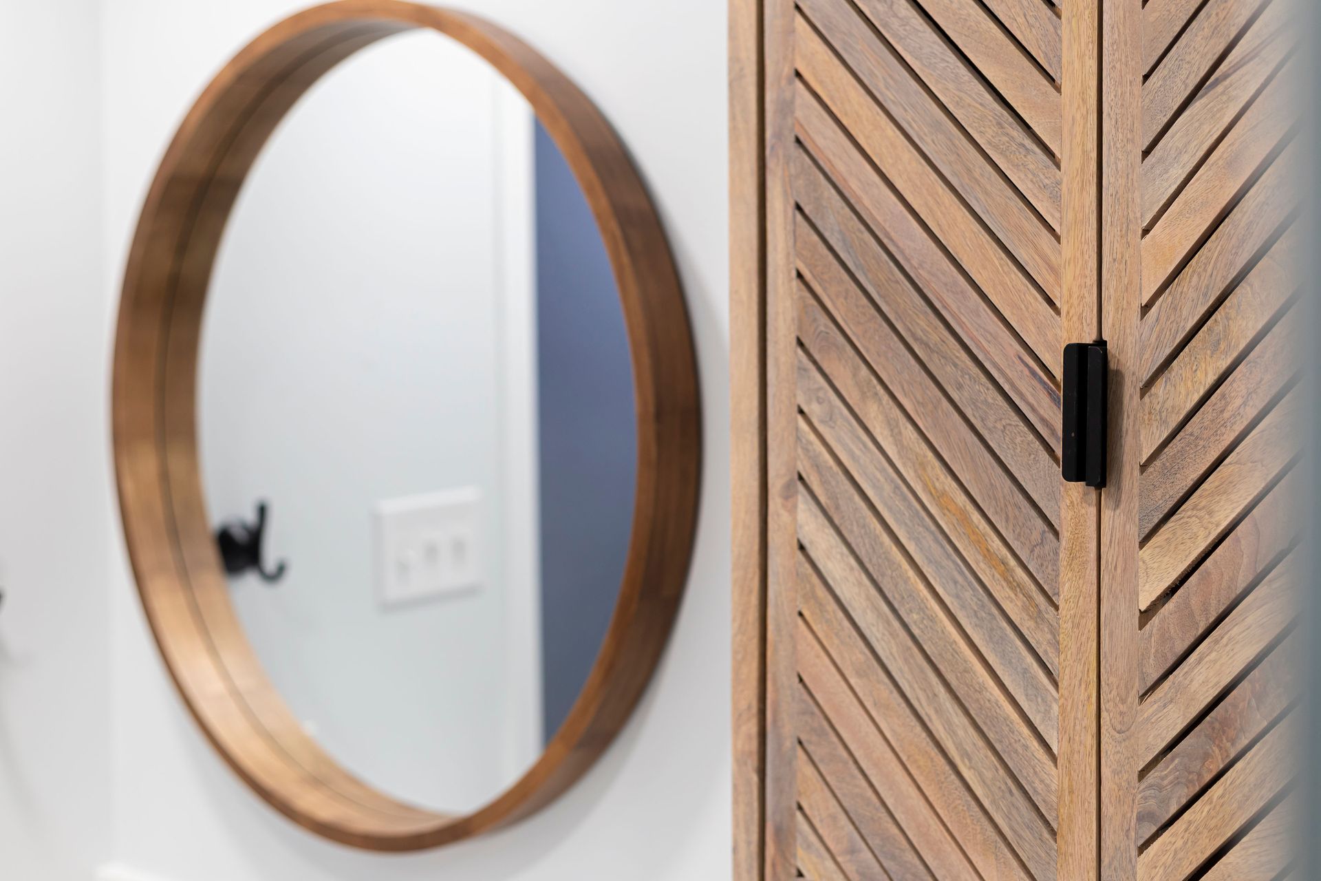 Detail of the round wood mirror and the chevron-pattern wood storage cabinet in the Howard County bathroom.