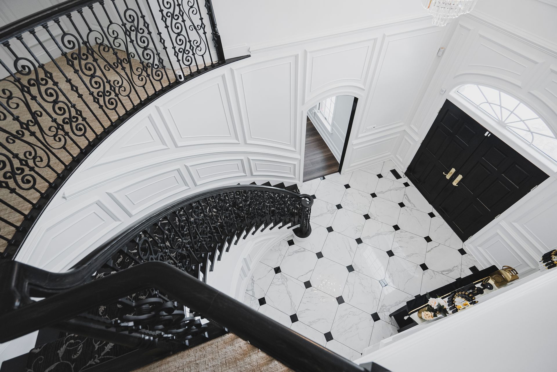 Newly installed large-format white marble tiles with black diamond inlay in a foyer.