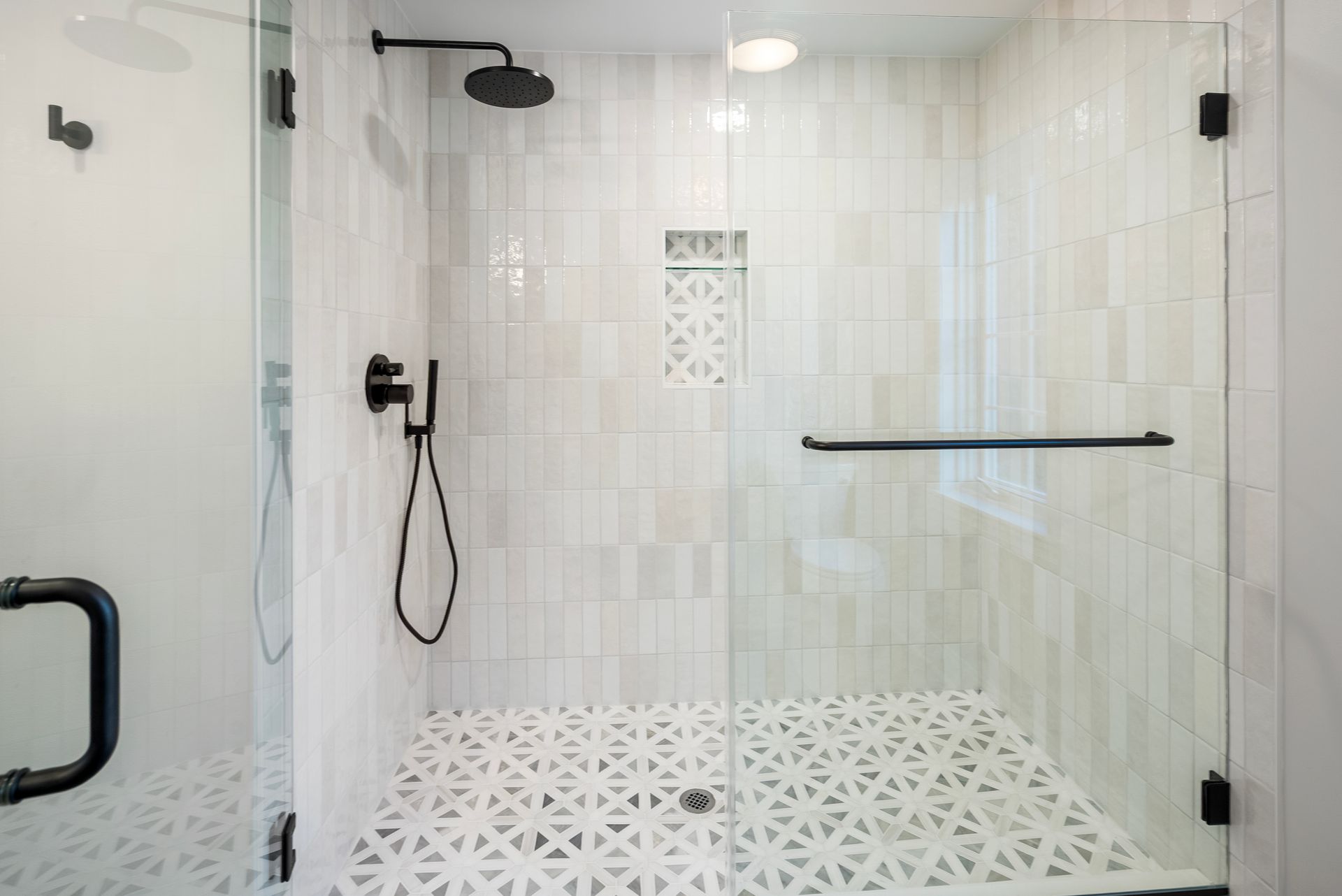 Custom built-in shower niche surrounded by vertically stacked glossy tile