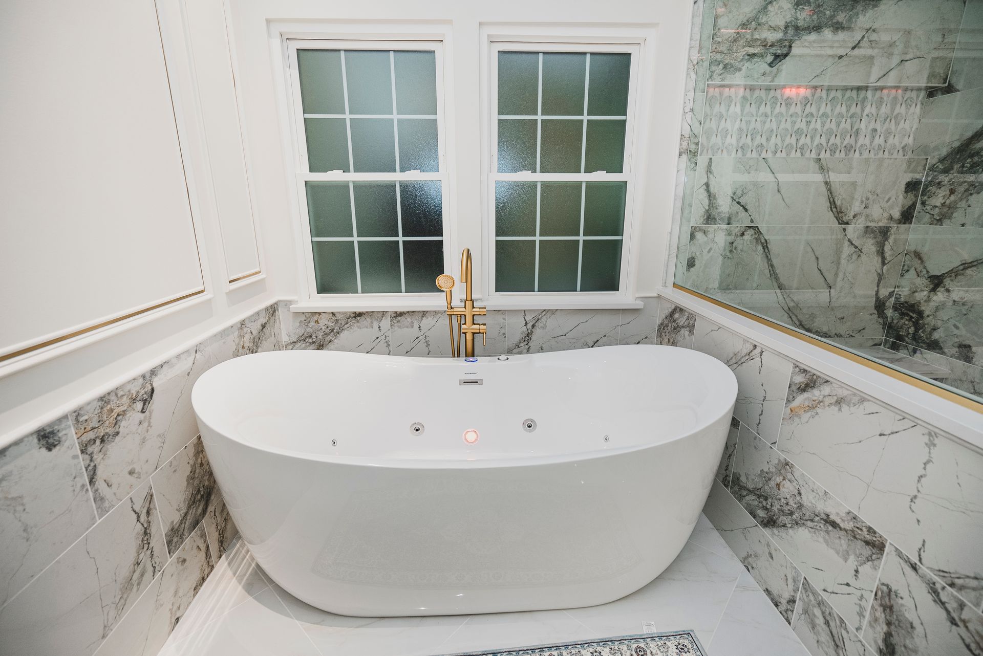 Freestanding whirlpool Jacuzzi tub with gold accent wall molding.