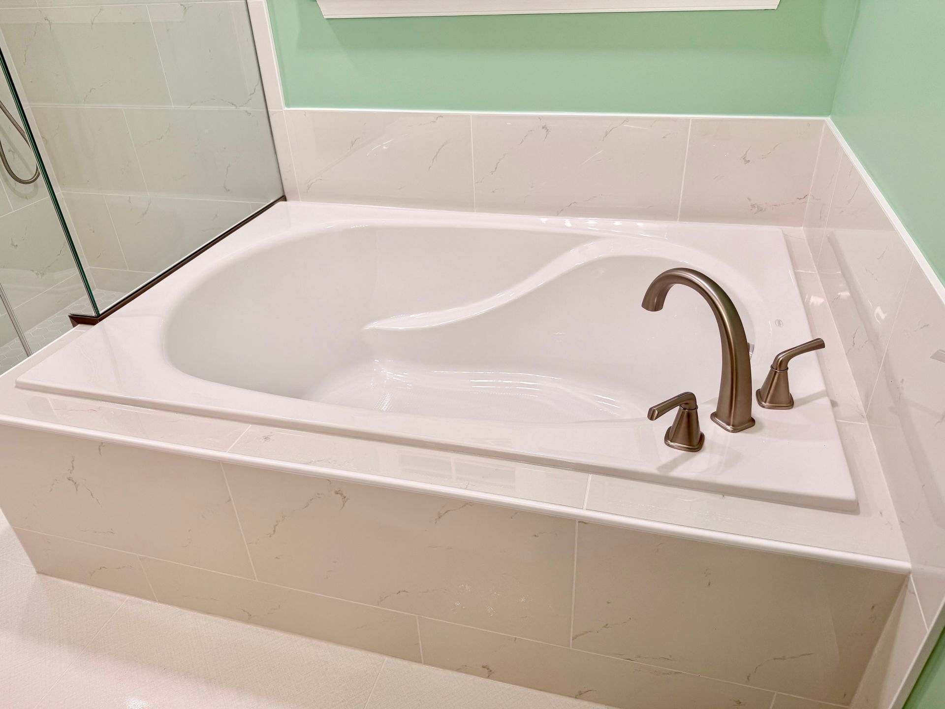 Professional plumbing and tile work demonstrated on the installed soaking tub and adjacent shower area.