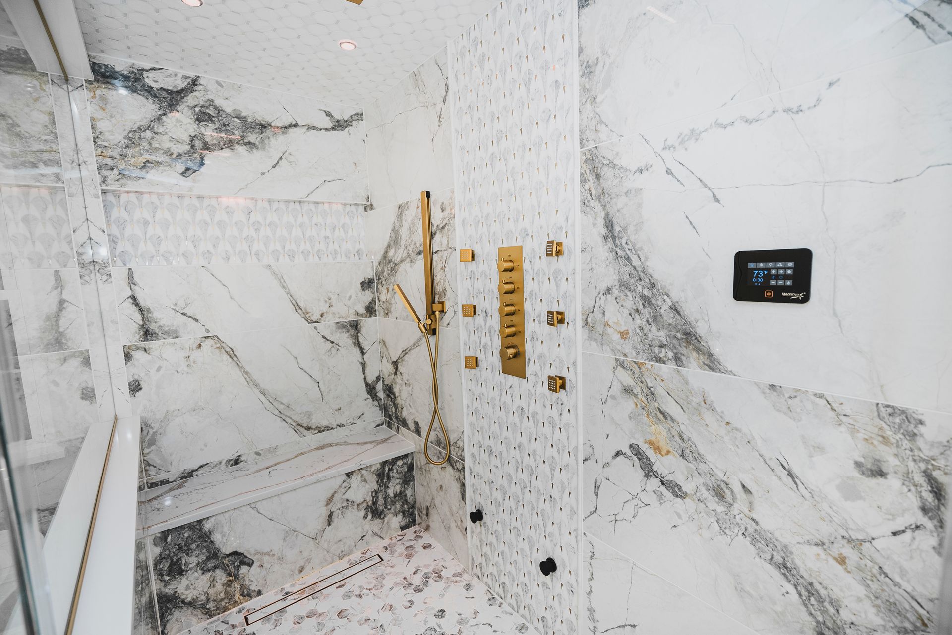 Walk-in steam shower with marble porcelain tile and built-in bench.
