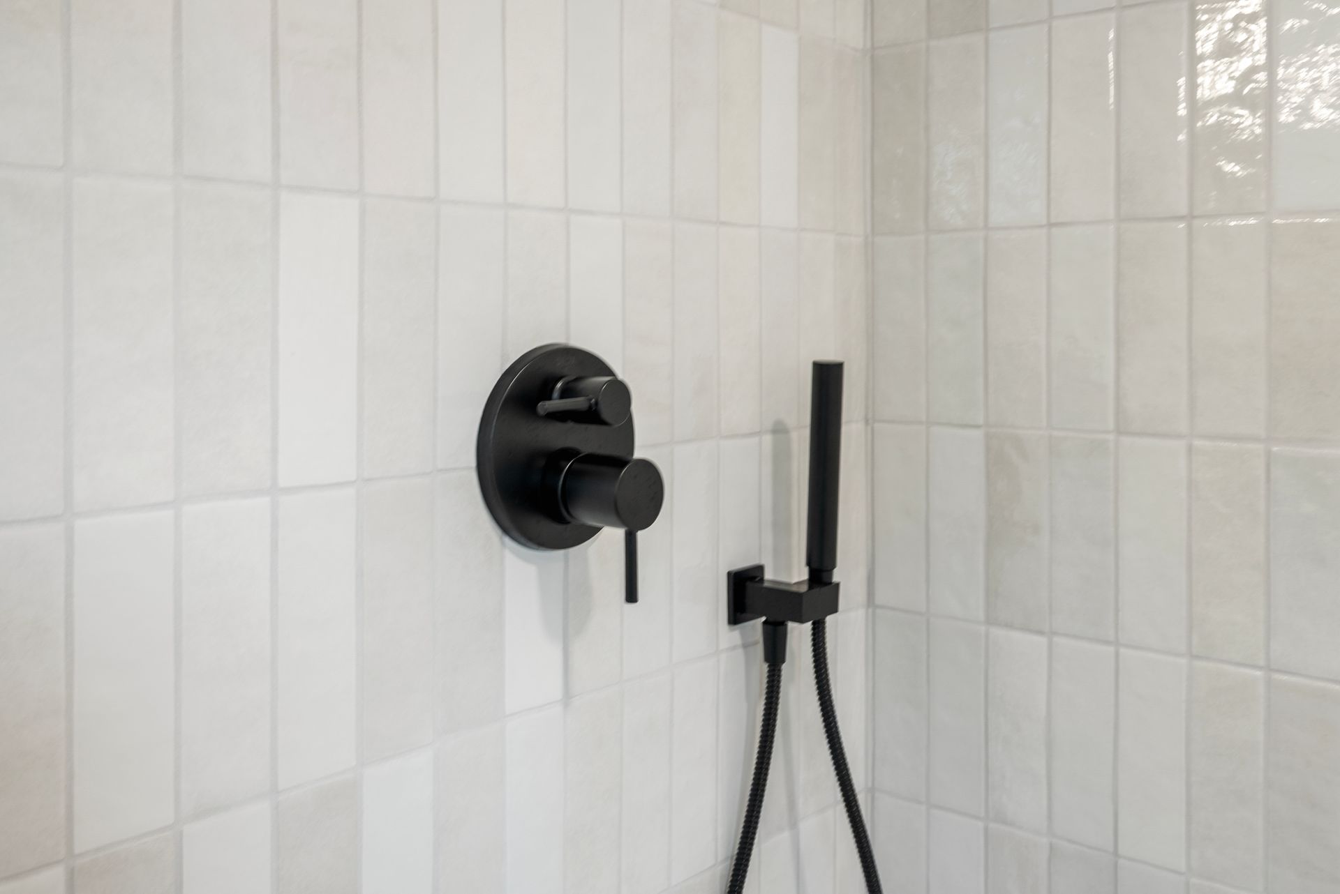 Bright walk-in shower featuring vertical subway wall tiles and a glass door