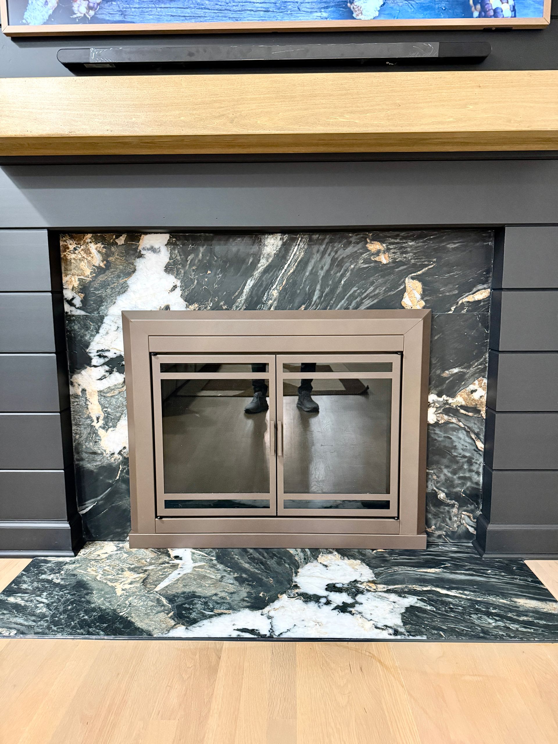 Expert stone installation showing dramatic natural marble veining and reflective firebox trim.