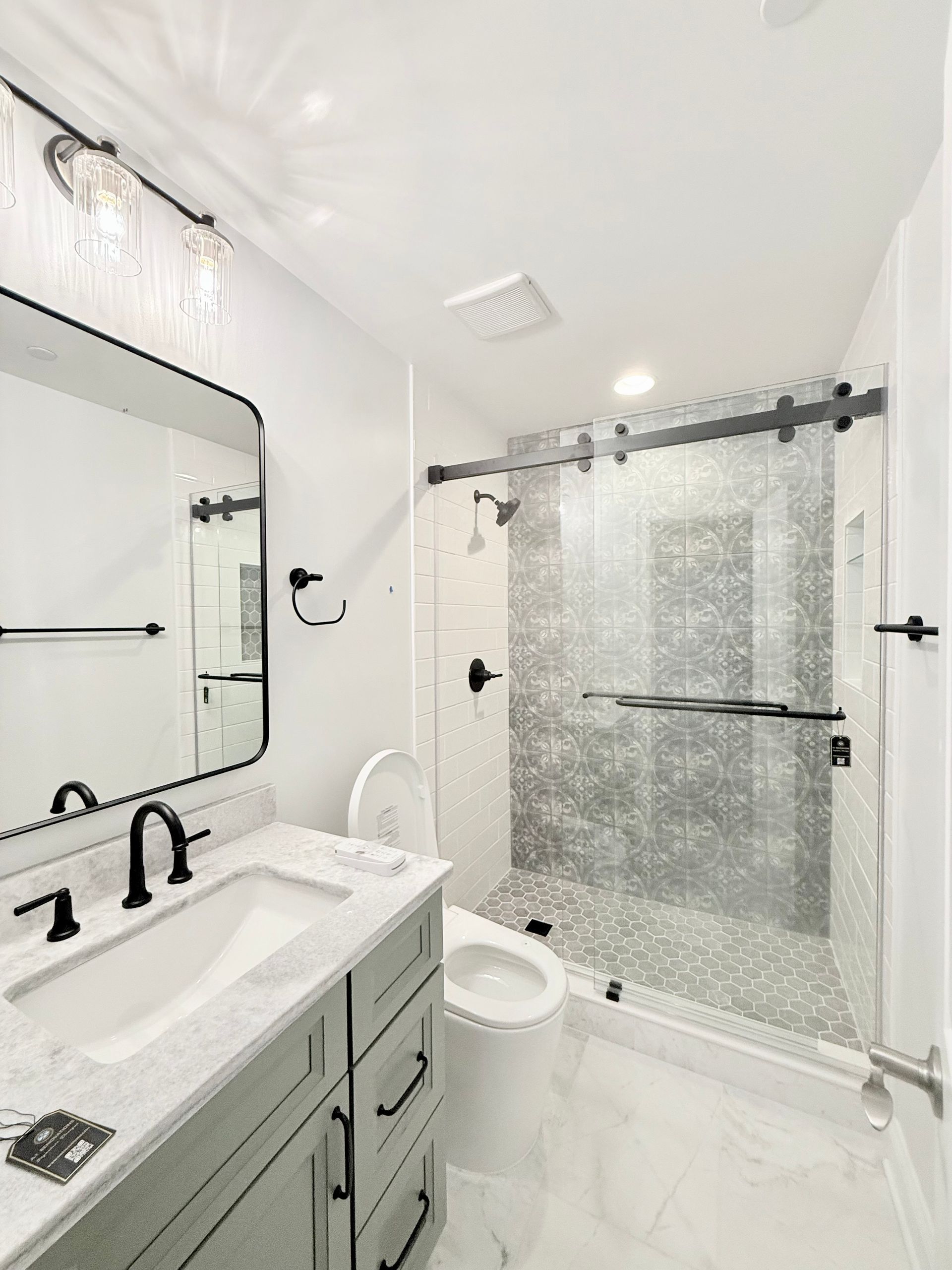 A spacious walk-in shower with a glass sliding door and matte black hardware in a Hampstead bathroom remodel.