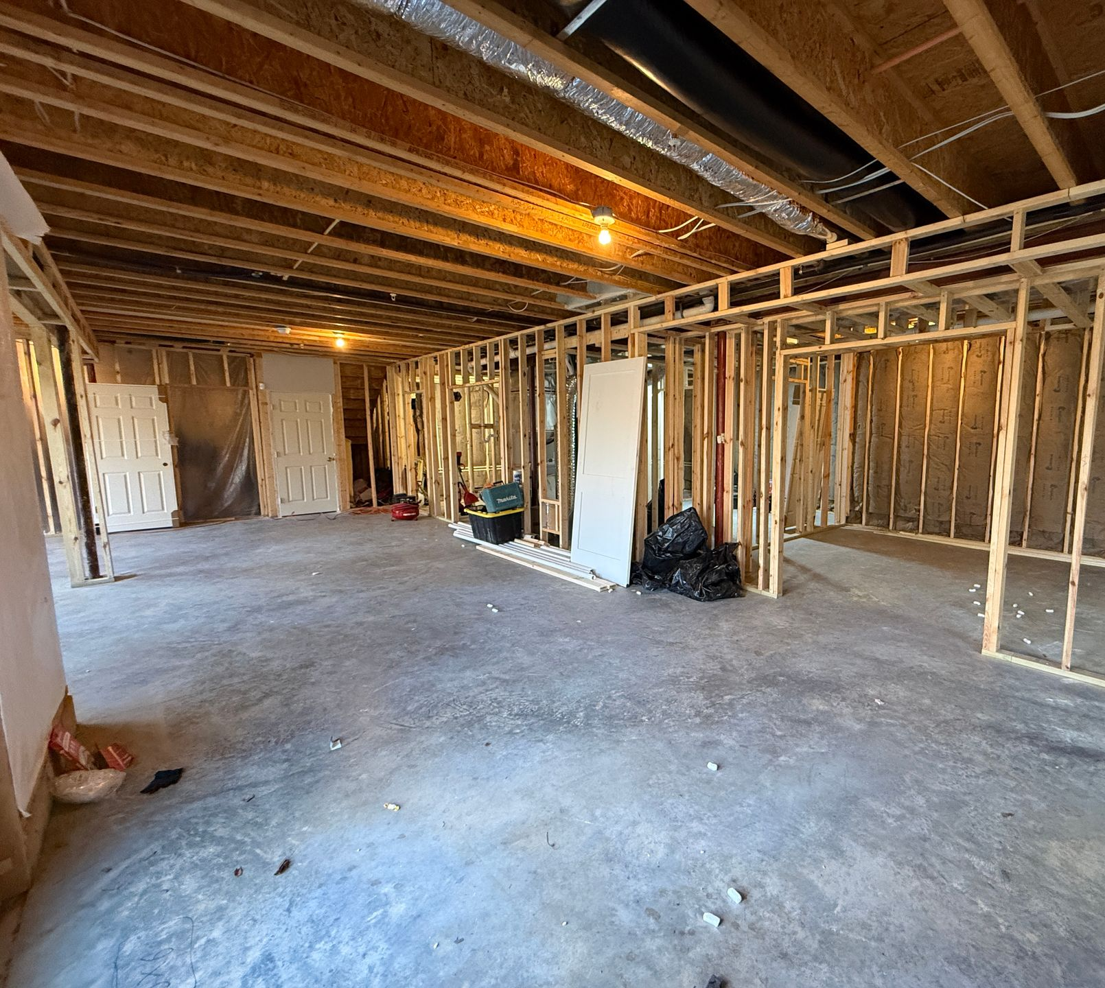 Raw basement framing and electrical panel layout showing open joists and exposed ductwork.