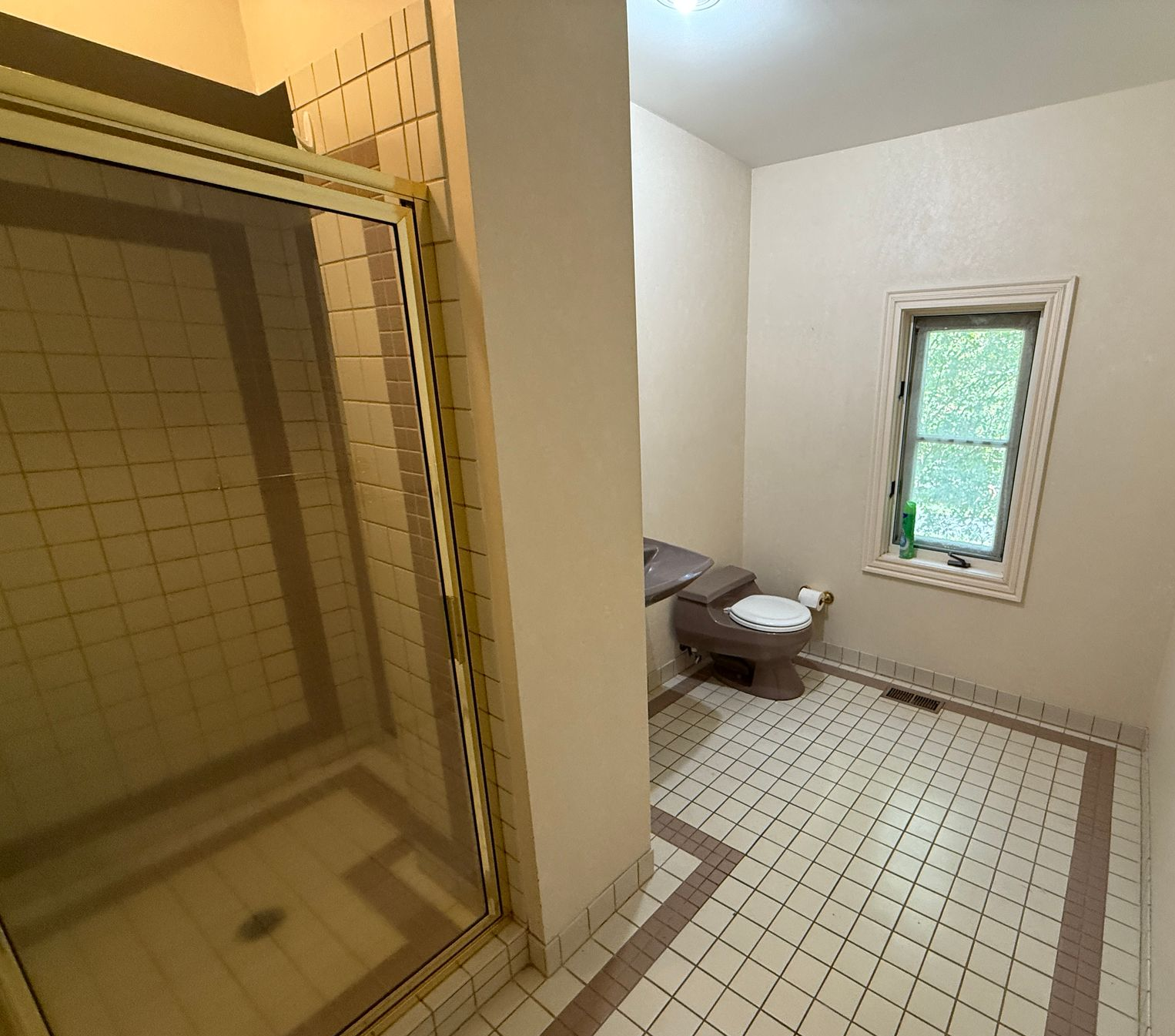 A dated bathroom with a pink toilet, sink, and an ornate gold mirror.
