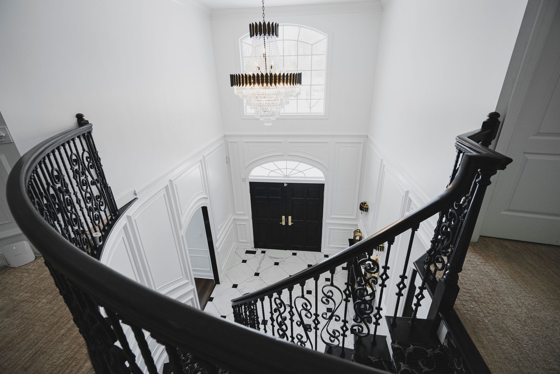 High-end entryway remodel featuring elegant wall paneling and a grand crystal chandelier.
