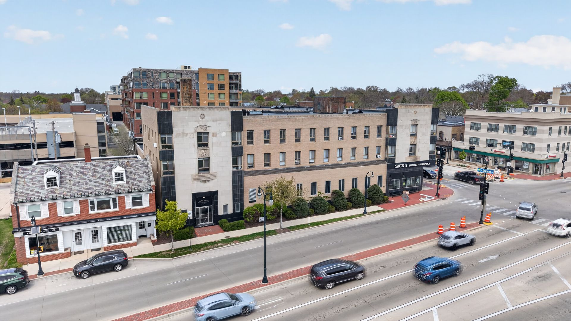 City street with cars, mixed low-rise buildings, and a busy roadway on a clear day