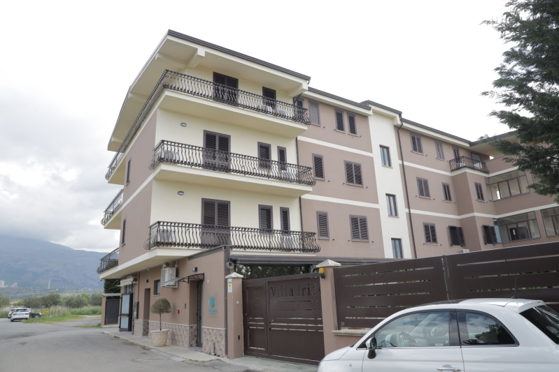 Un condominio a più piani di colore beige e marrone con balconi in ferro battuto e ingresso con cancello.