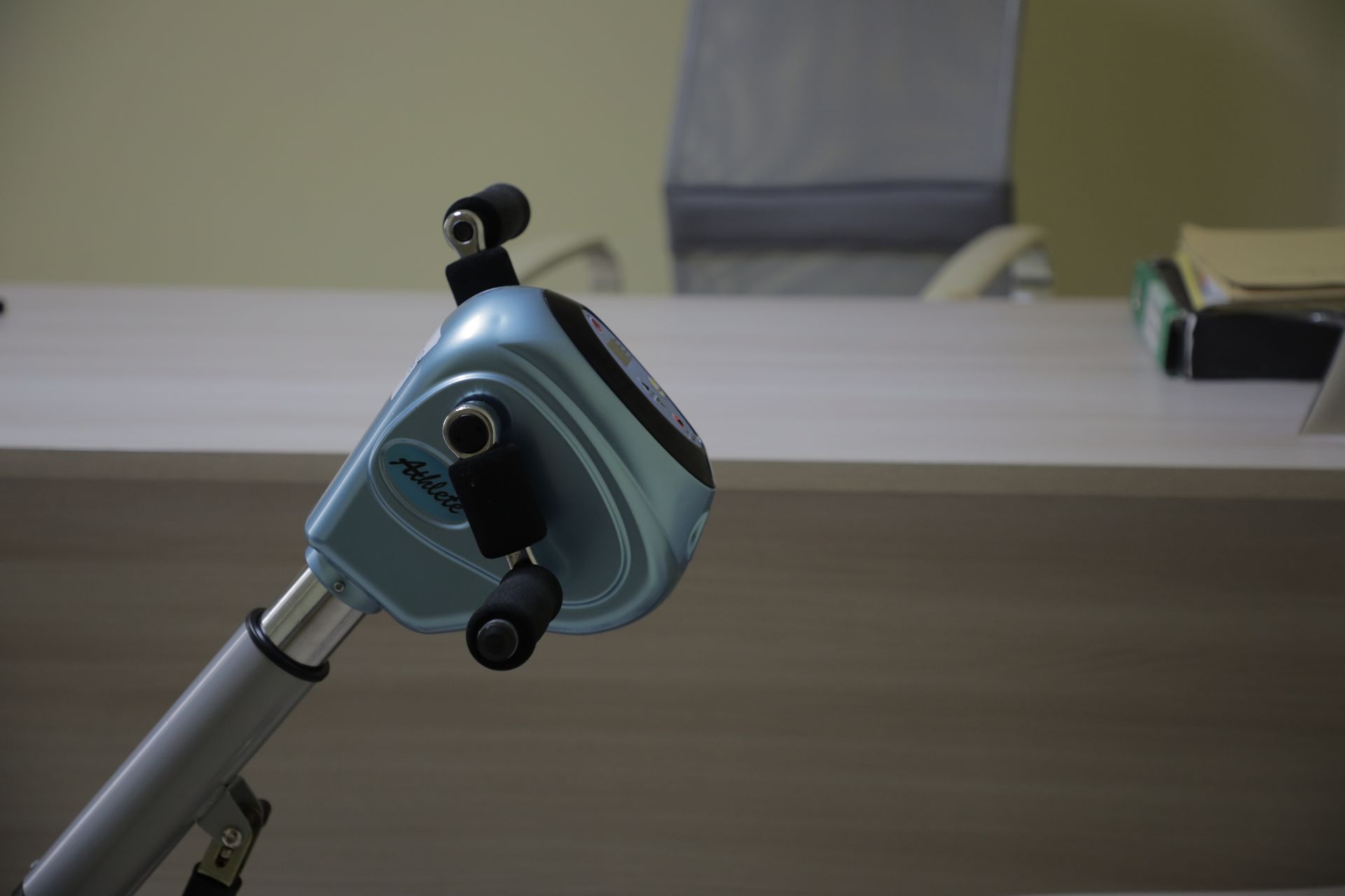 Primo piano della console azzurra di una cyclette a pedali in un ambiente d'ufficio.