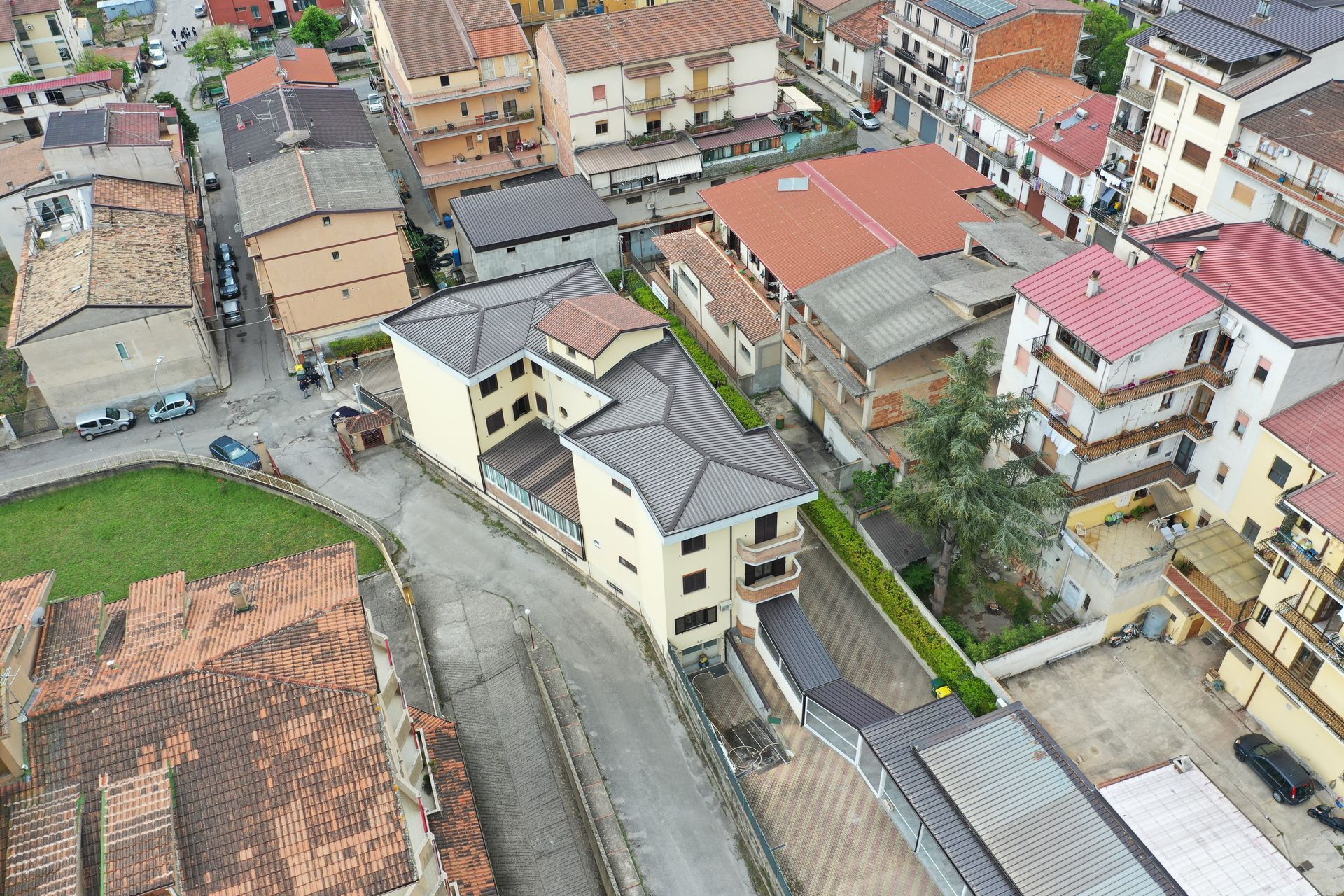 Veduta aerea di una città con strade strette, edifici chiari con tetti grigi e tetti di tegole rosse.
