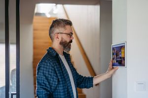 Man in blue shirt using a wall-mounted touchscreen in a hallway