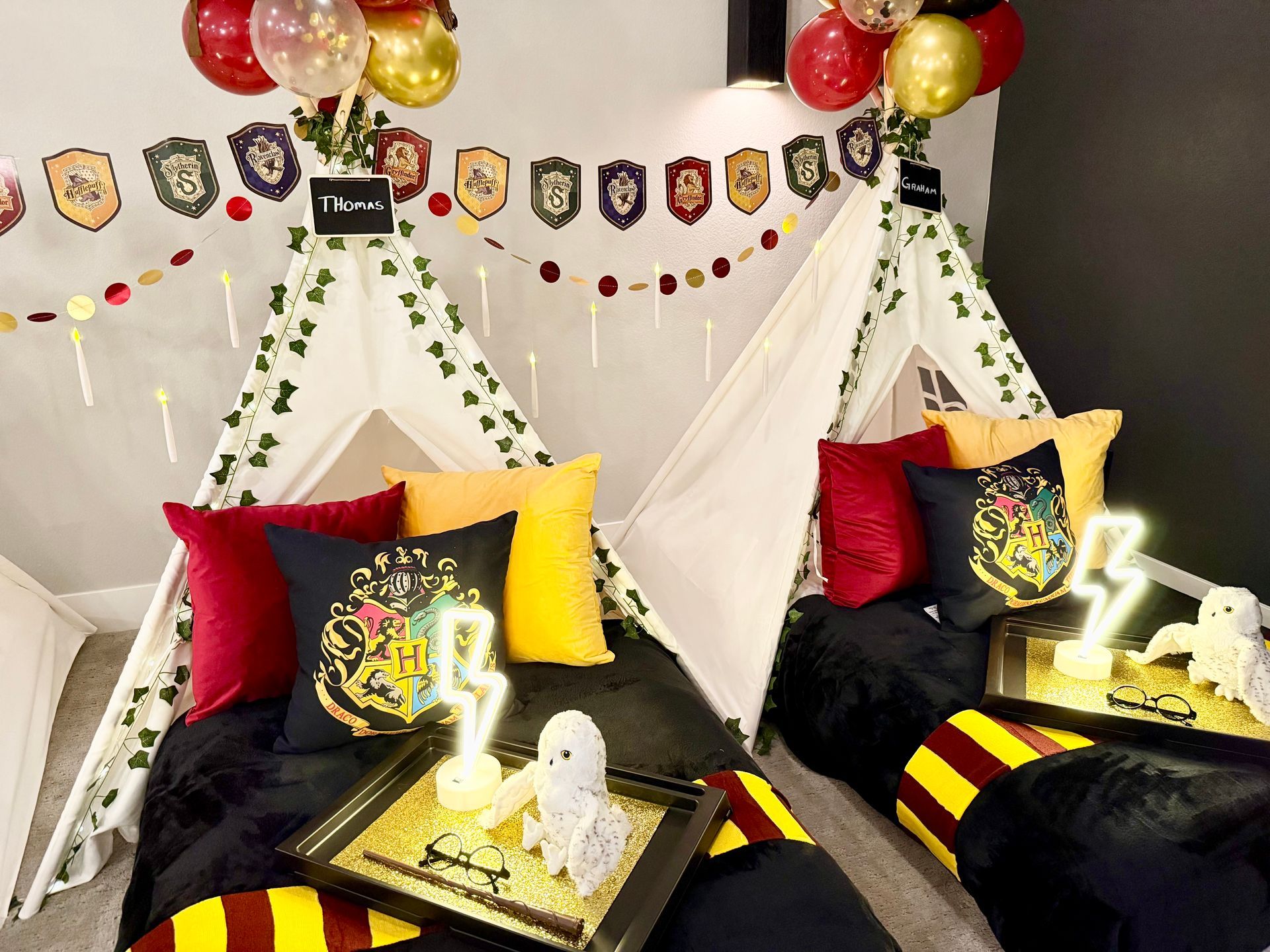 Harry Potter decorated tent sleepover setup with black, red, and yellow bedding, balloons, and floating lights