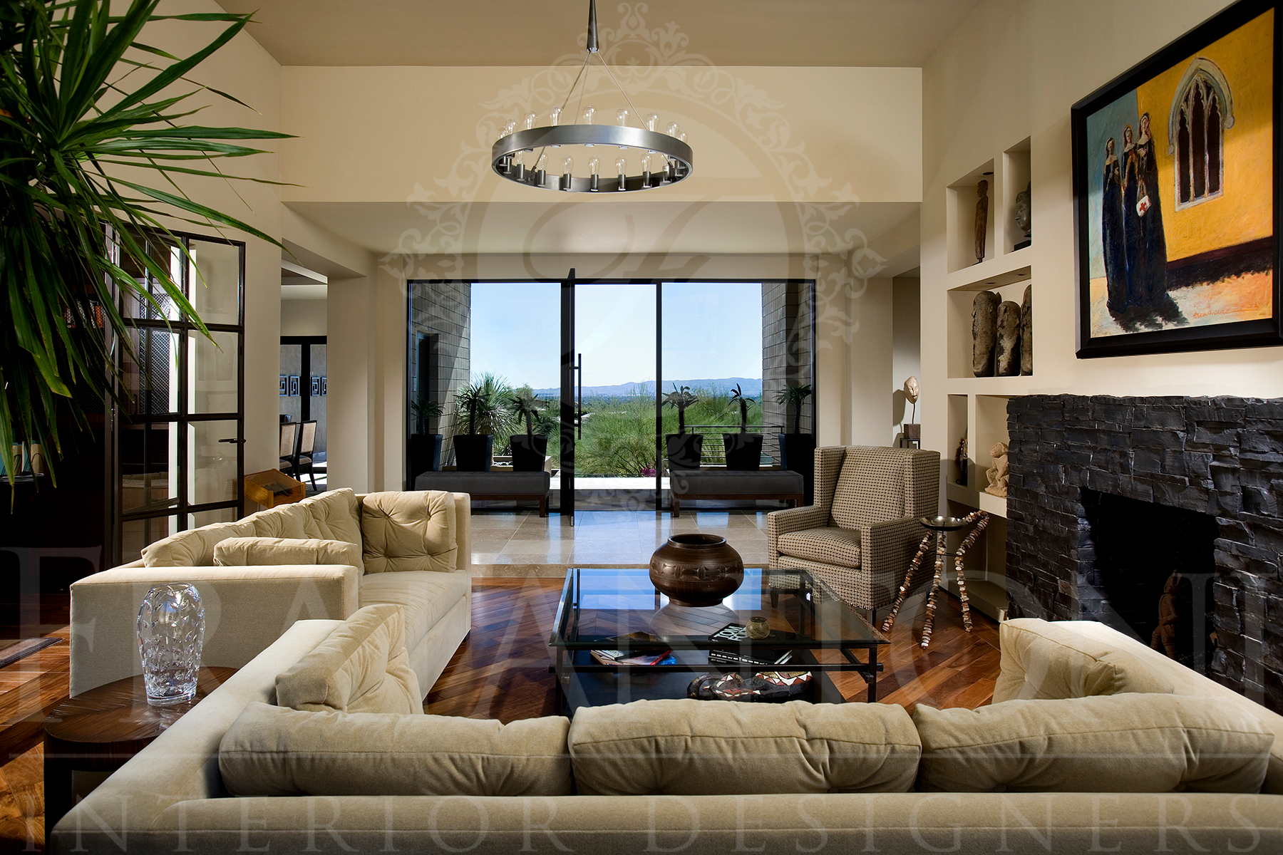 A luxurious living room with beige sofas, a glass coffee table, a stone fireplace, and a large view through sliding doors.