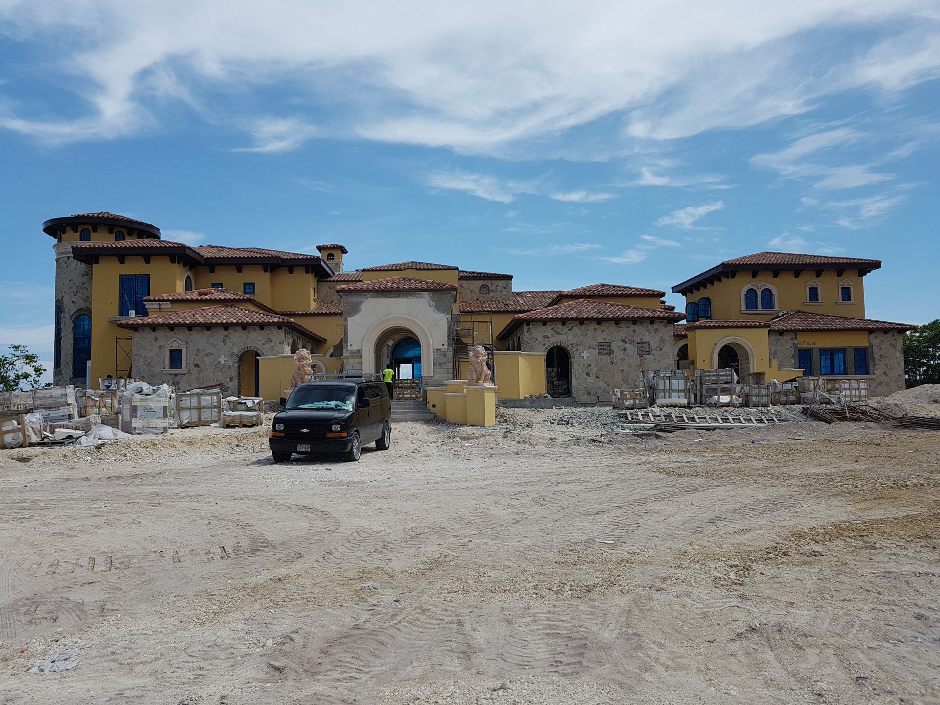 Large yellow and stone building under construction; blue sky above.