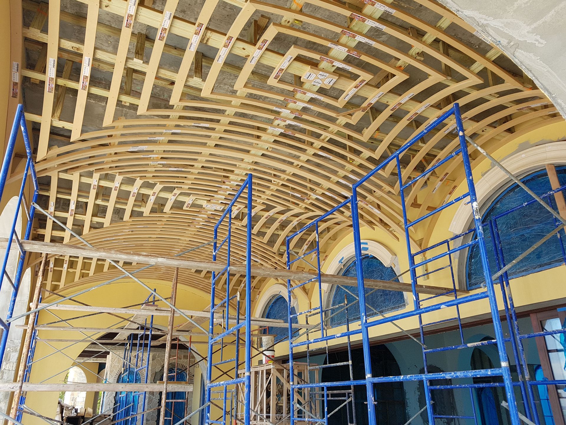 Wooden framework of an arched ceiling under construction; scaffolding supports the structure.