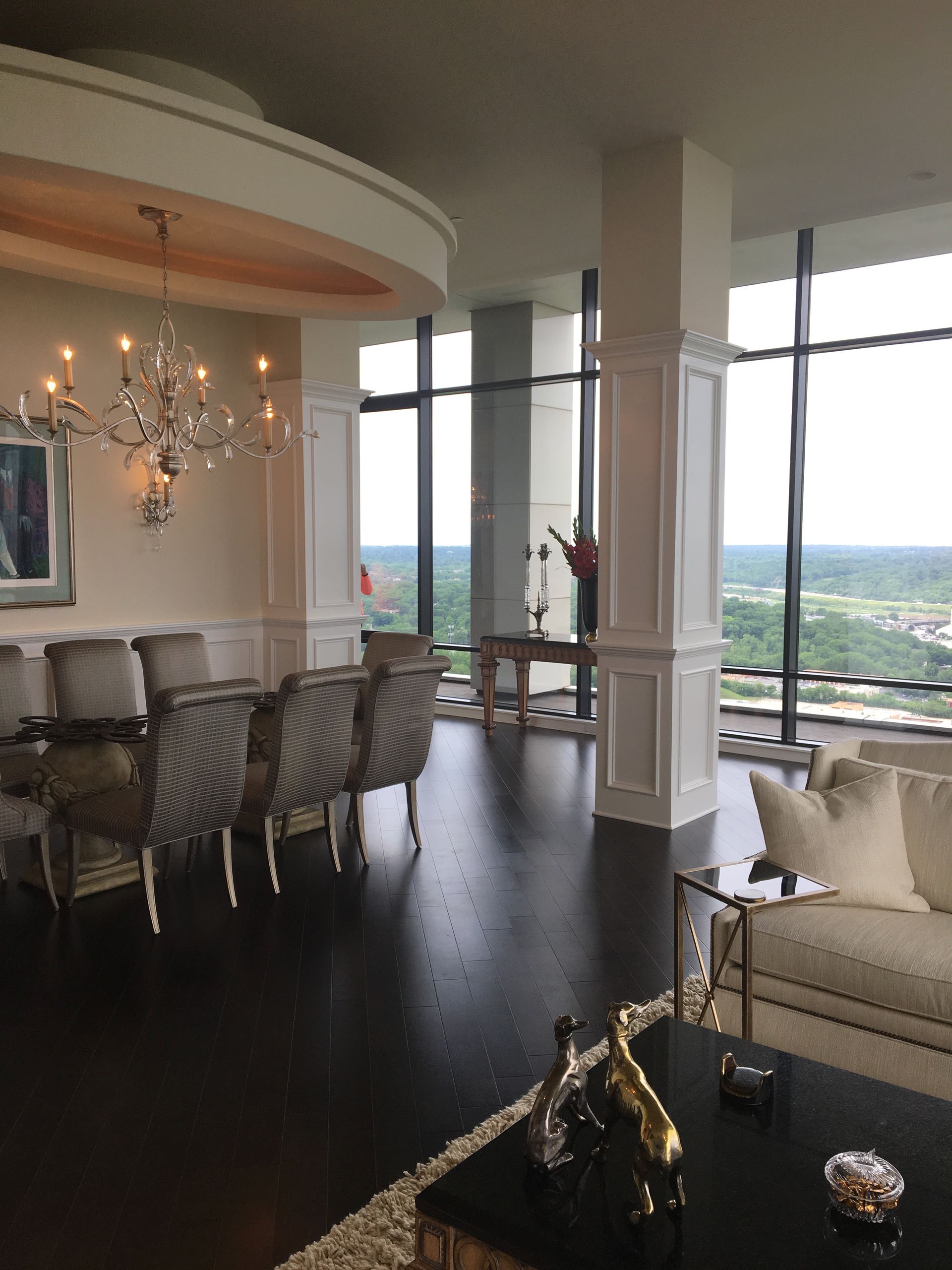 A living room with a couch , chairs , a table and a chandelier