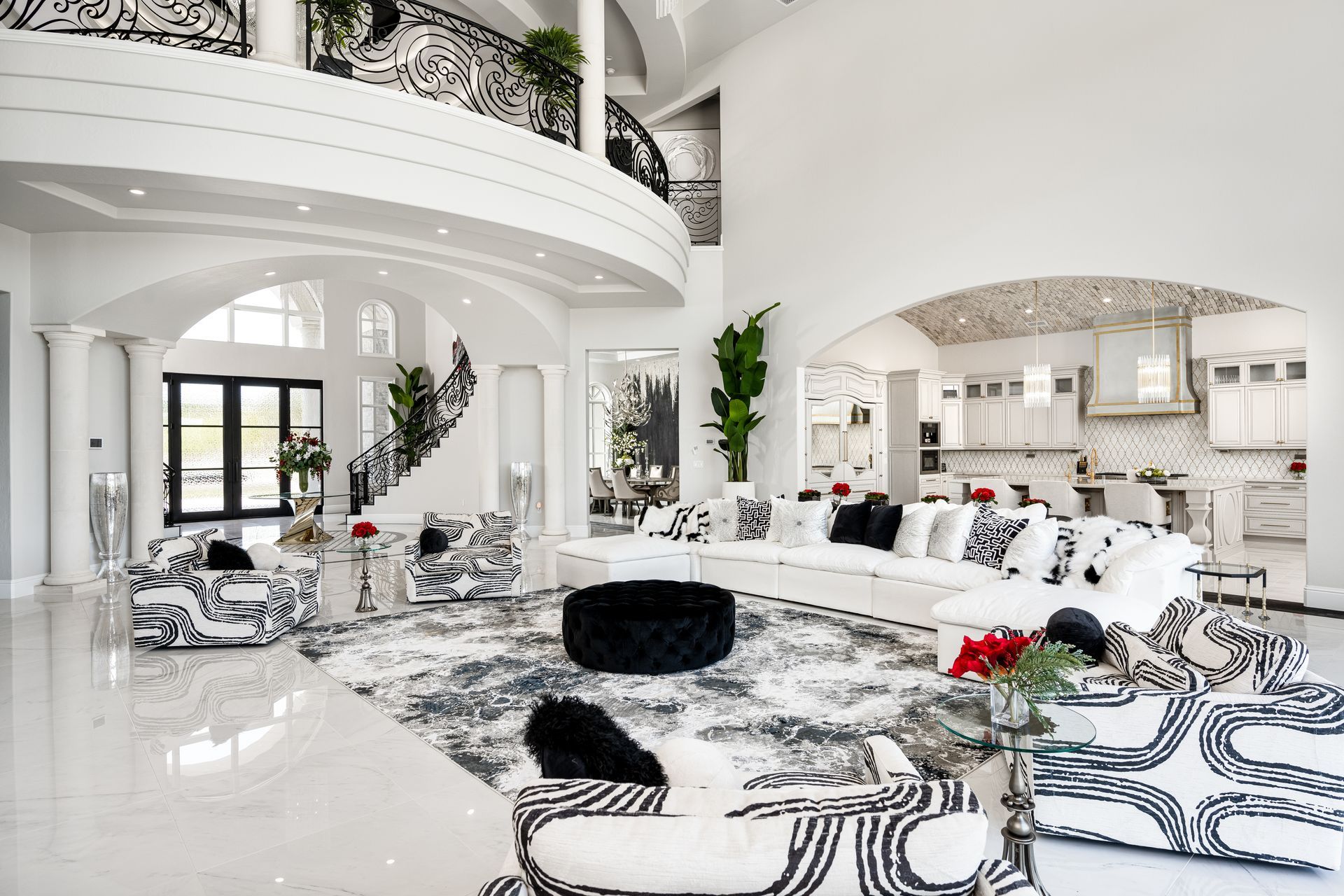 Luxurious white interior with zebra-print furniture, large rug, and arched doorways, near a kitchen and balcony.