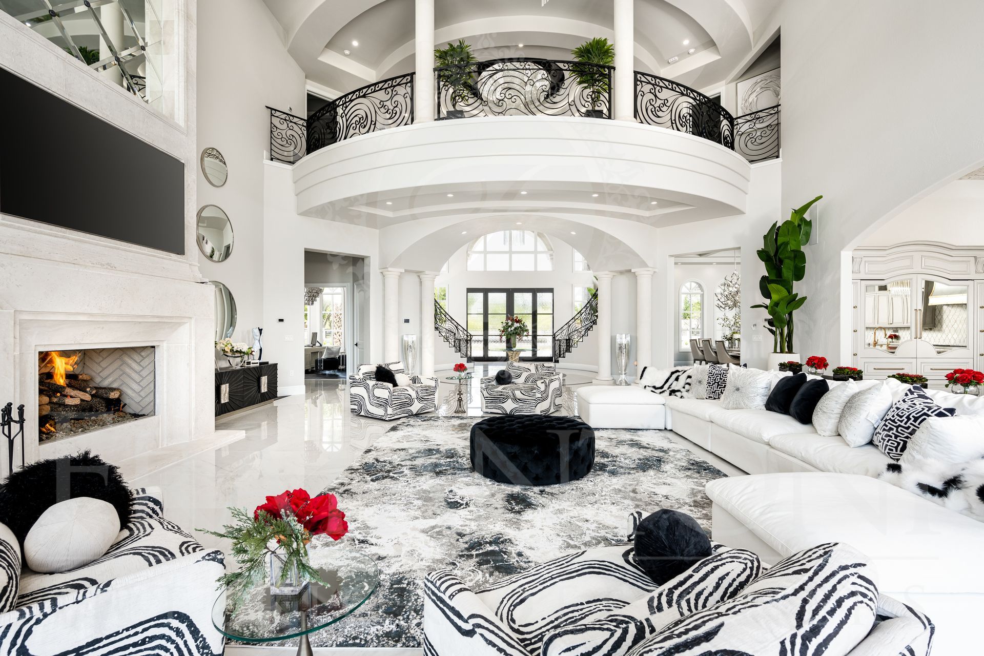 Luxurious white living room with black and white print accents, fireplace, and balcony.