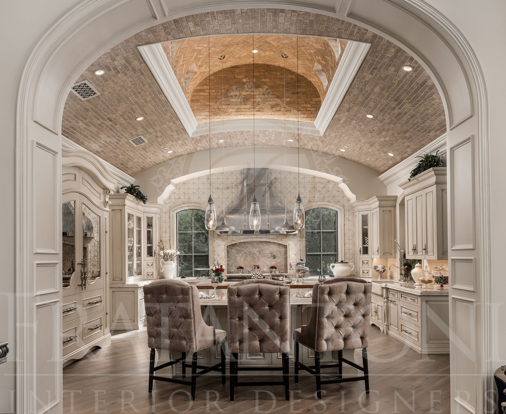 Elegant neutral kitchen with a brick vaulted ceiling, marble double islands, hanging pendant lights, a stainless steel range hood, custom paneled refrigerator, and tufted chairs designed by Fratantoni Interior Designers in scottsdale Arizona.