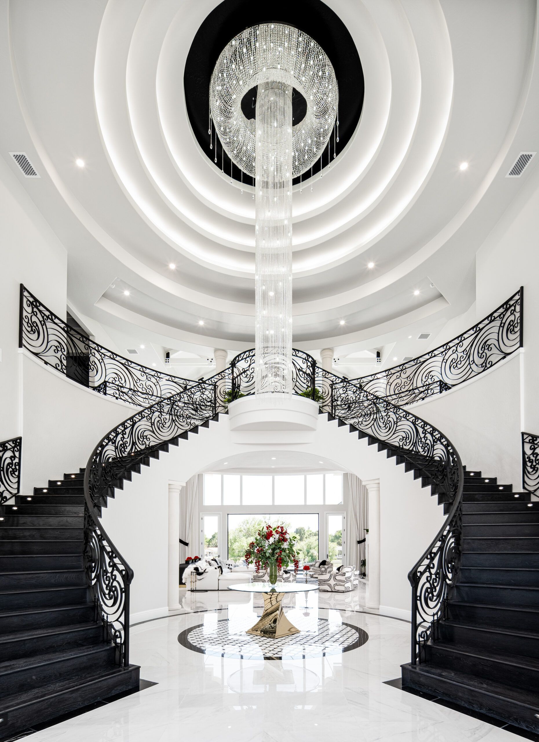 A black and white staircase with a chandelier hanging from the ceiling