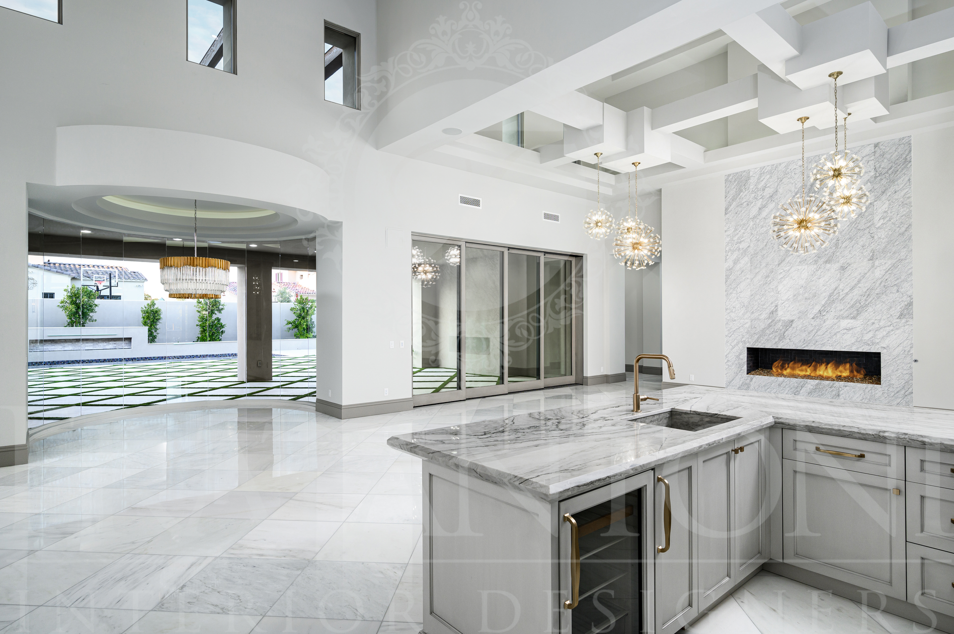 Bright modern open-plan kitchen and living area with white marble floors, island, and fireplace in Scottsdale, Arizona
