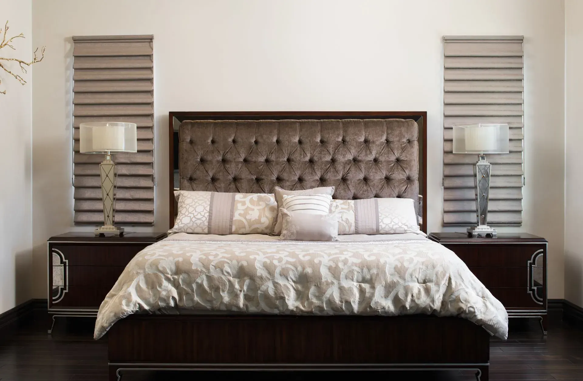 Bedroom with a bed, tufted headboard, nightstands, lamps, and patterned bedding.