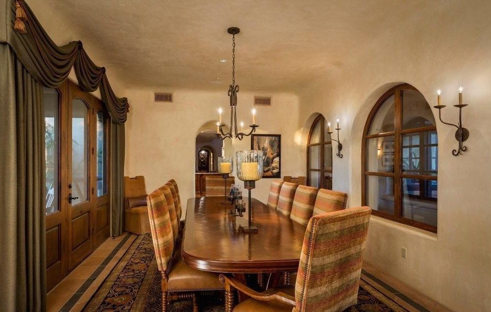 A dining room with a long table and chairs and a chandelier hanging from the ceiling.