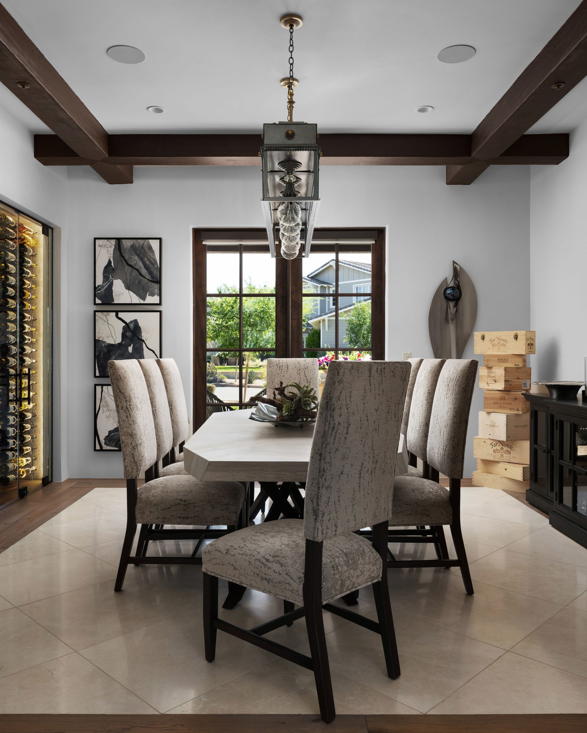 Elegant dining room: table with patterned chairs, chandelier, dark wood beams and framed art.