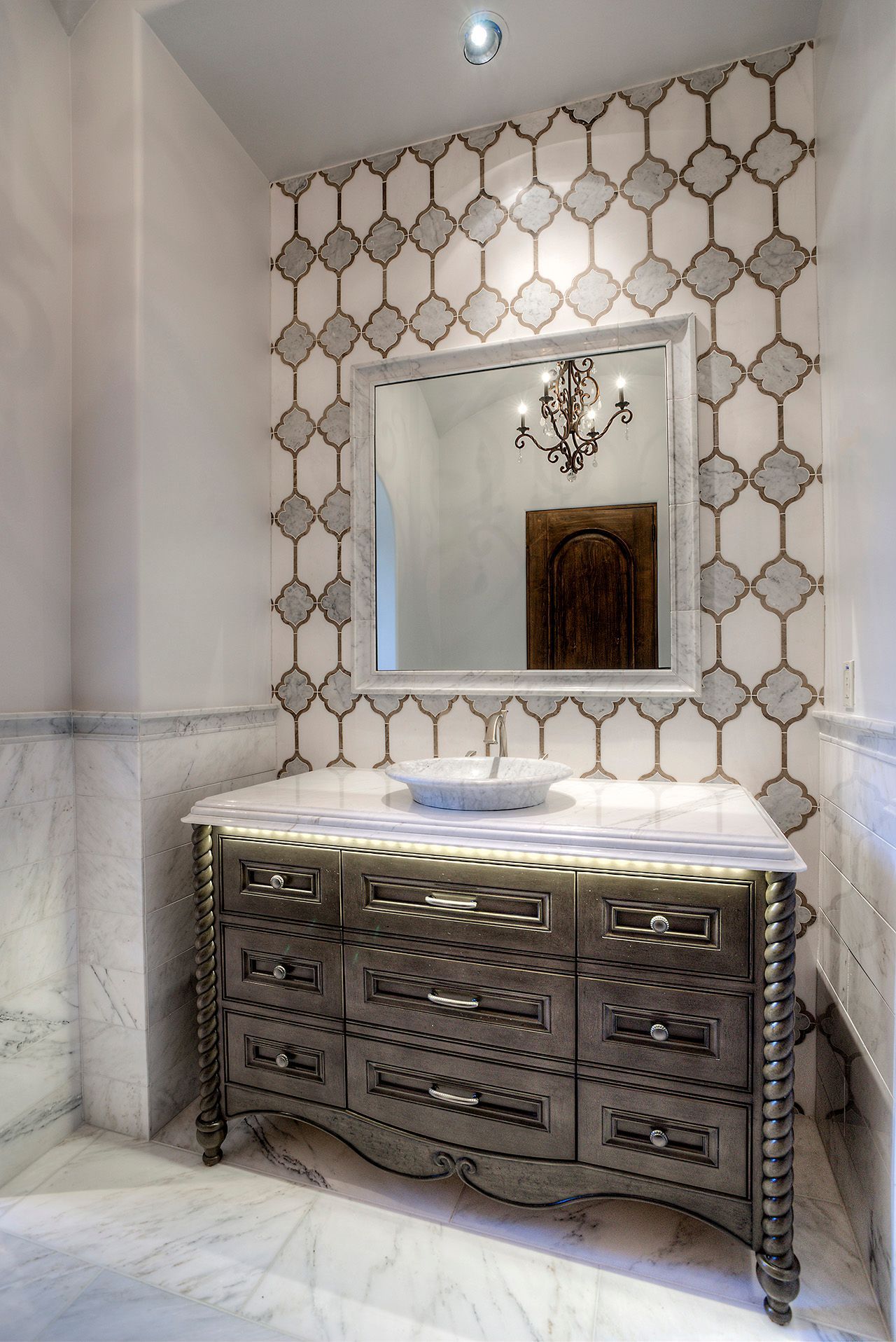 Elegant bathroom with gray vanity, patterned tile backsplash, and large mirror.