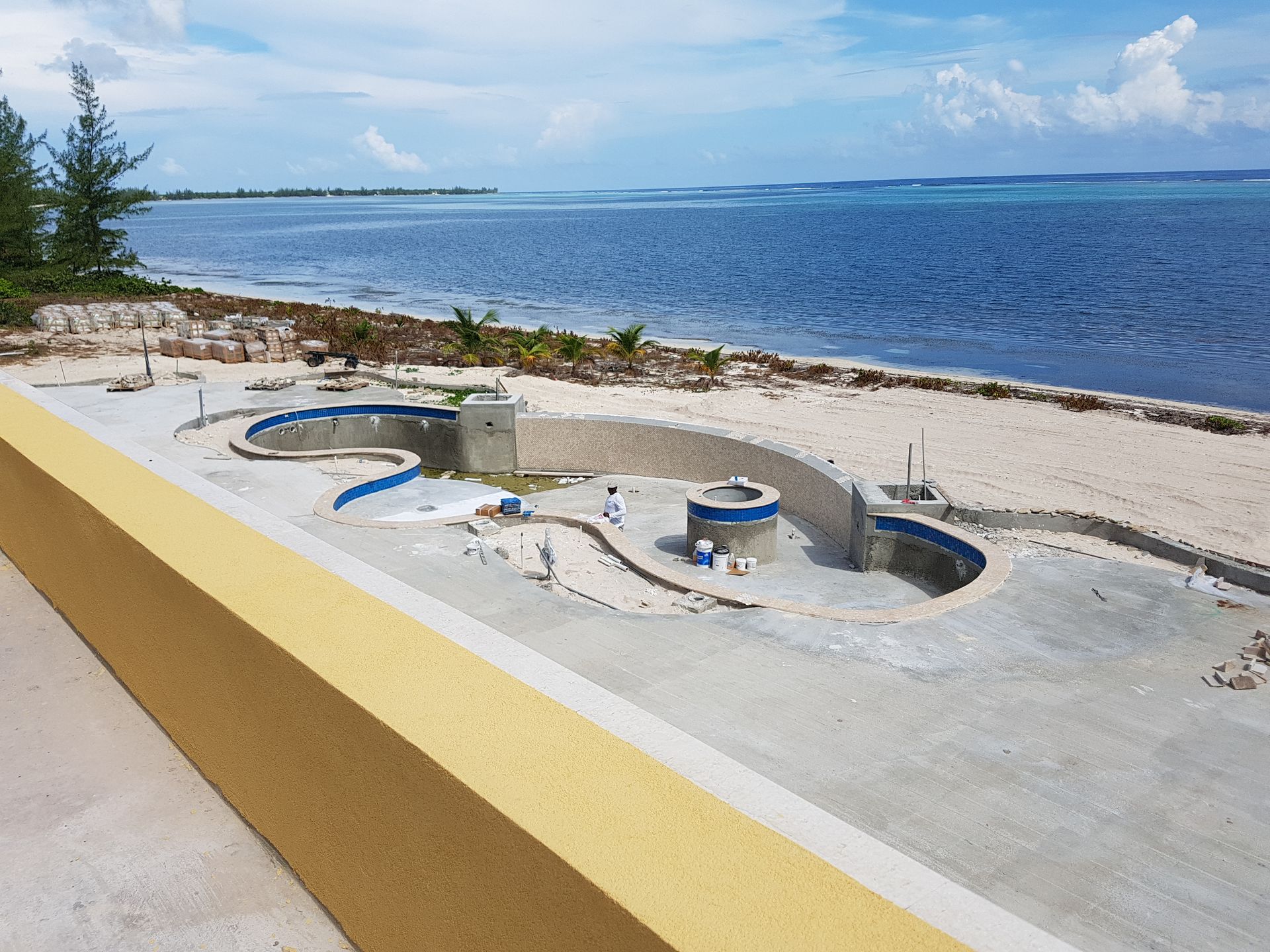 Construction site next to a beach with ocean view. Concrete foundation and circular walls.