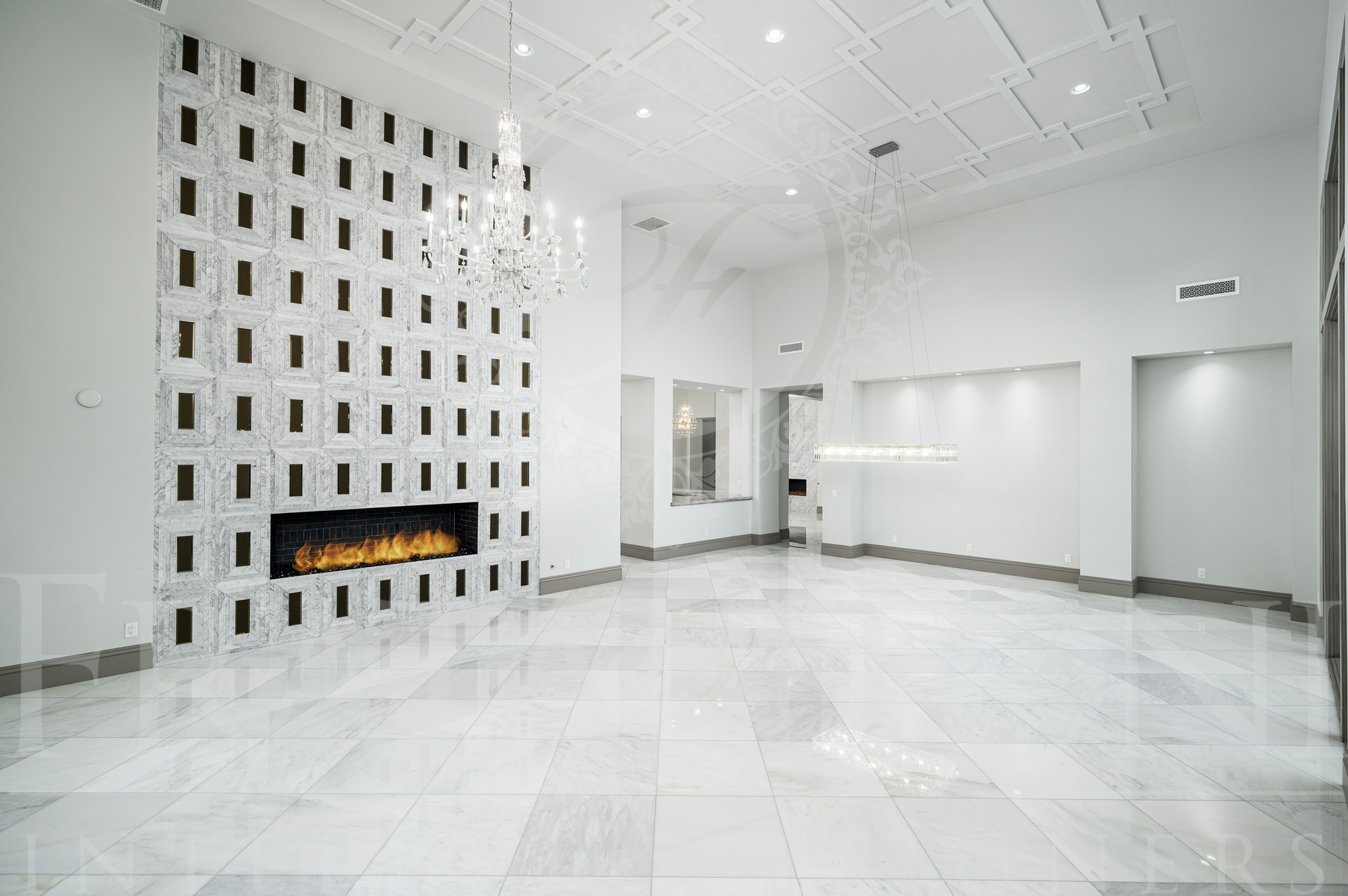Bright luxury great room with custom fireplace and crystal chandeliers.