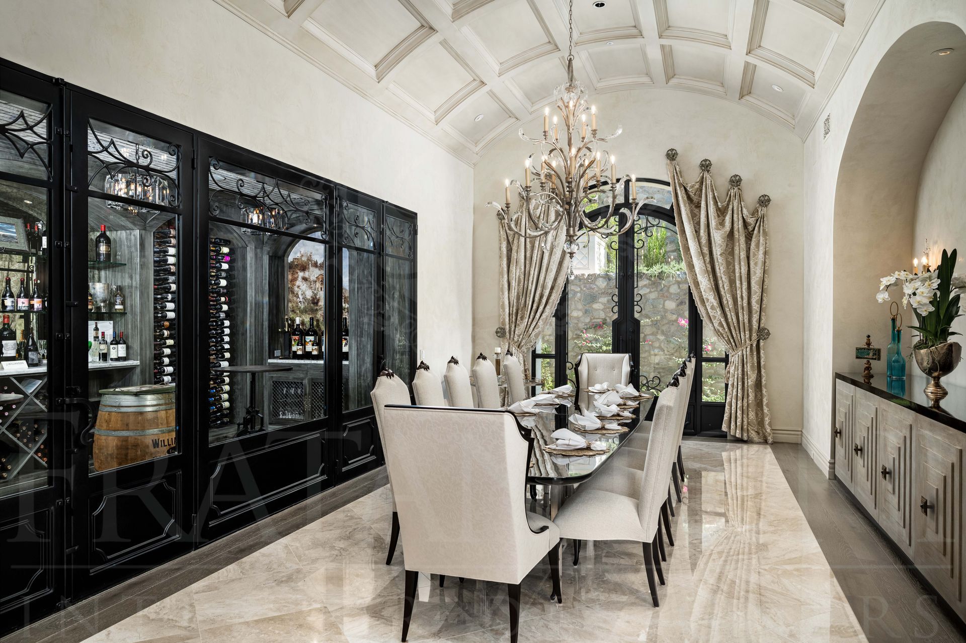 French style formal dining room featuring a long table with upholstered chairs, a crystal chandelier, and a black-framed wine cellar in scottsdale, arizona