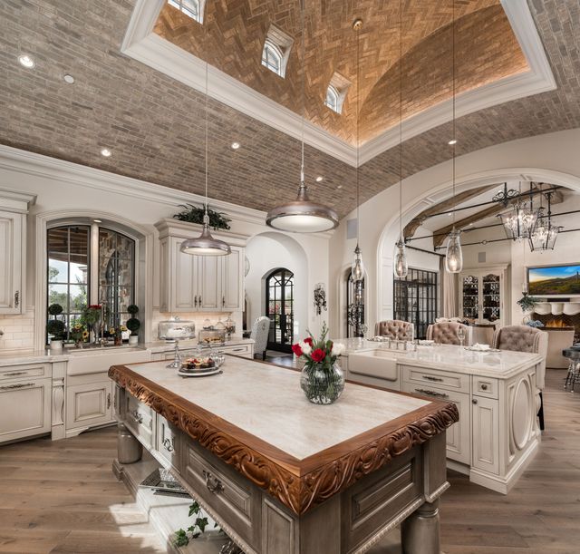 French villa kitchen interior design with dual islands, brick barrel ceiling and custom furnishings.