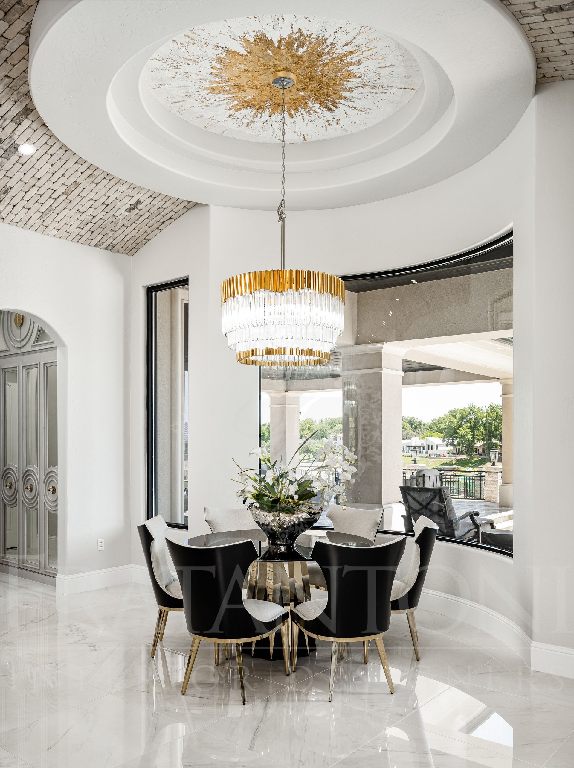 Luxurious breakfast nook with black chairs, gold accents, marble floors, a view of the pool, and a crystal chandelier.